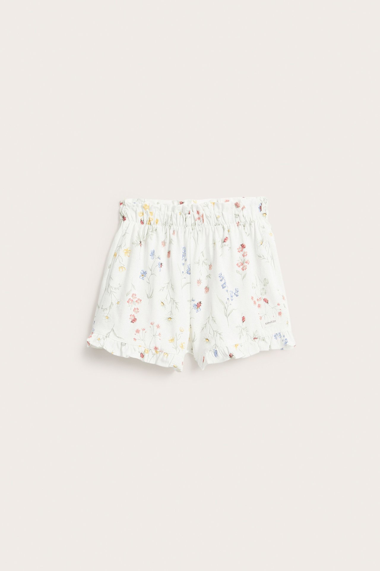 Framifrån: Offwhite jersey shorts med blommigt mönster, nyckelpigor, resårmidja, volangkanter.