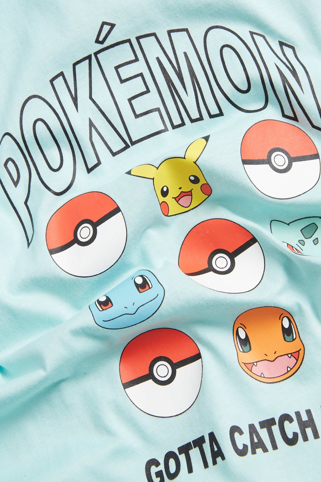 Zbliżenie na jasno-turkusowy bawełniany T-shirt dziecięcy z nadrukiem Pokémon i postaciami.