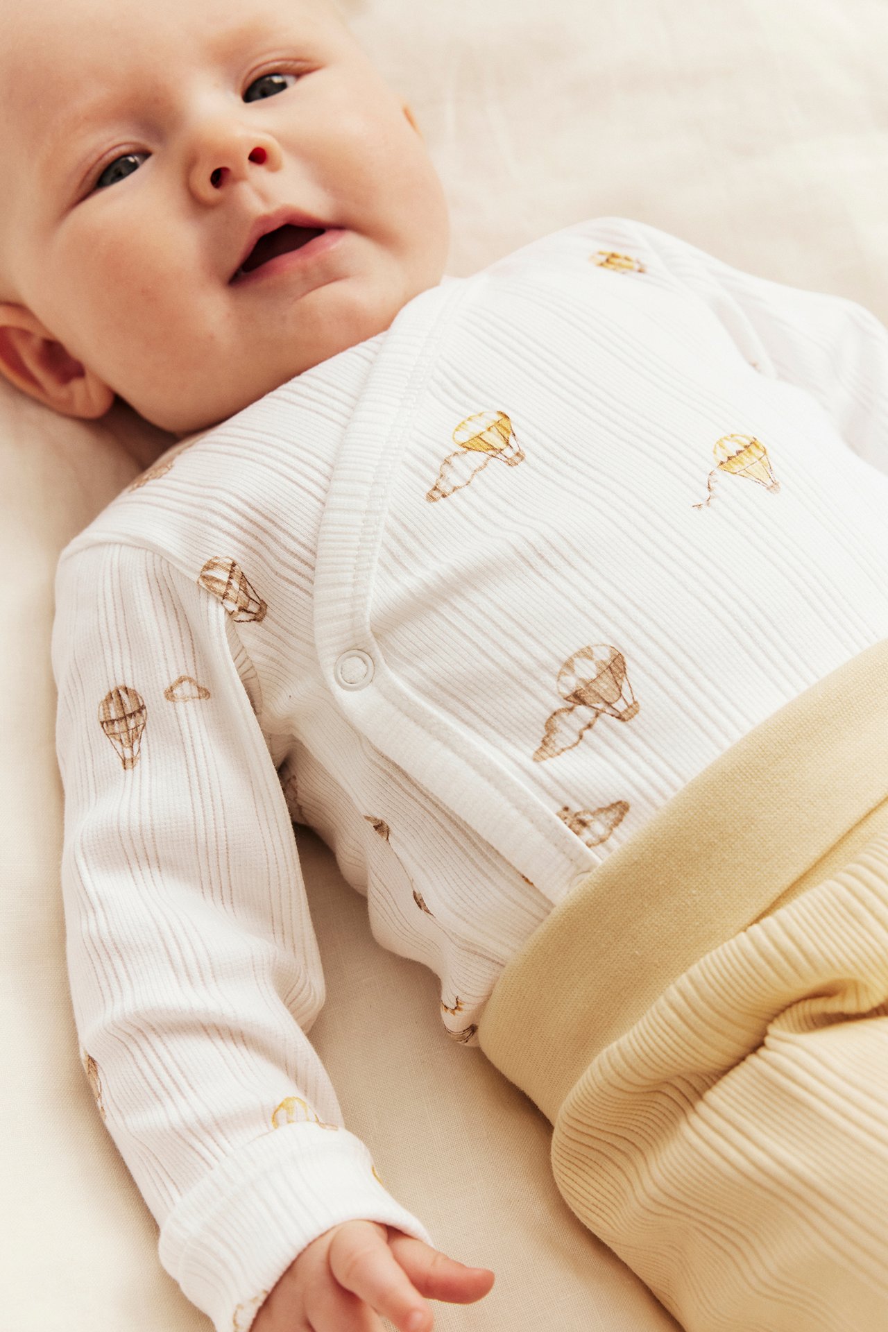 Babyns offwhite ribbade omlottbody med luftballongs-/nalletryck och gula ribbade byxor.