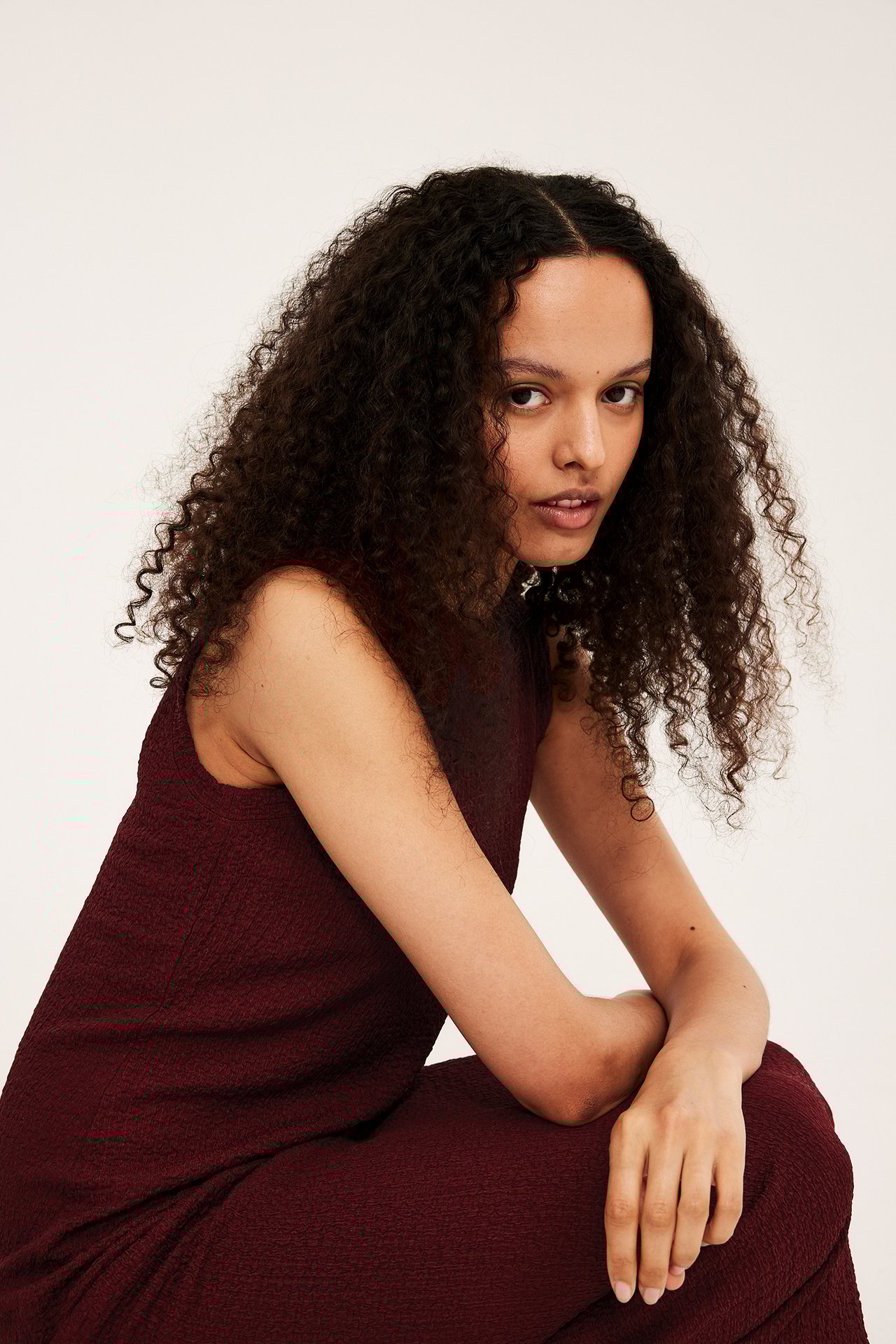 Närbild, framifrån, av en kvinna i röd strukturerad ärmlös midiklänning.