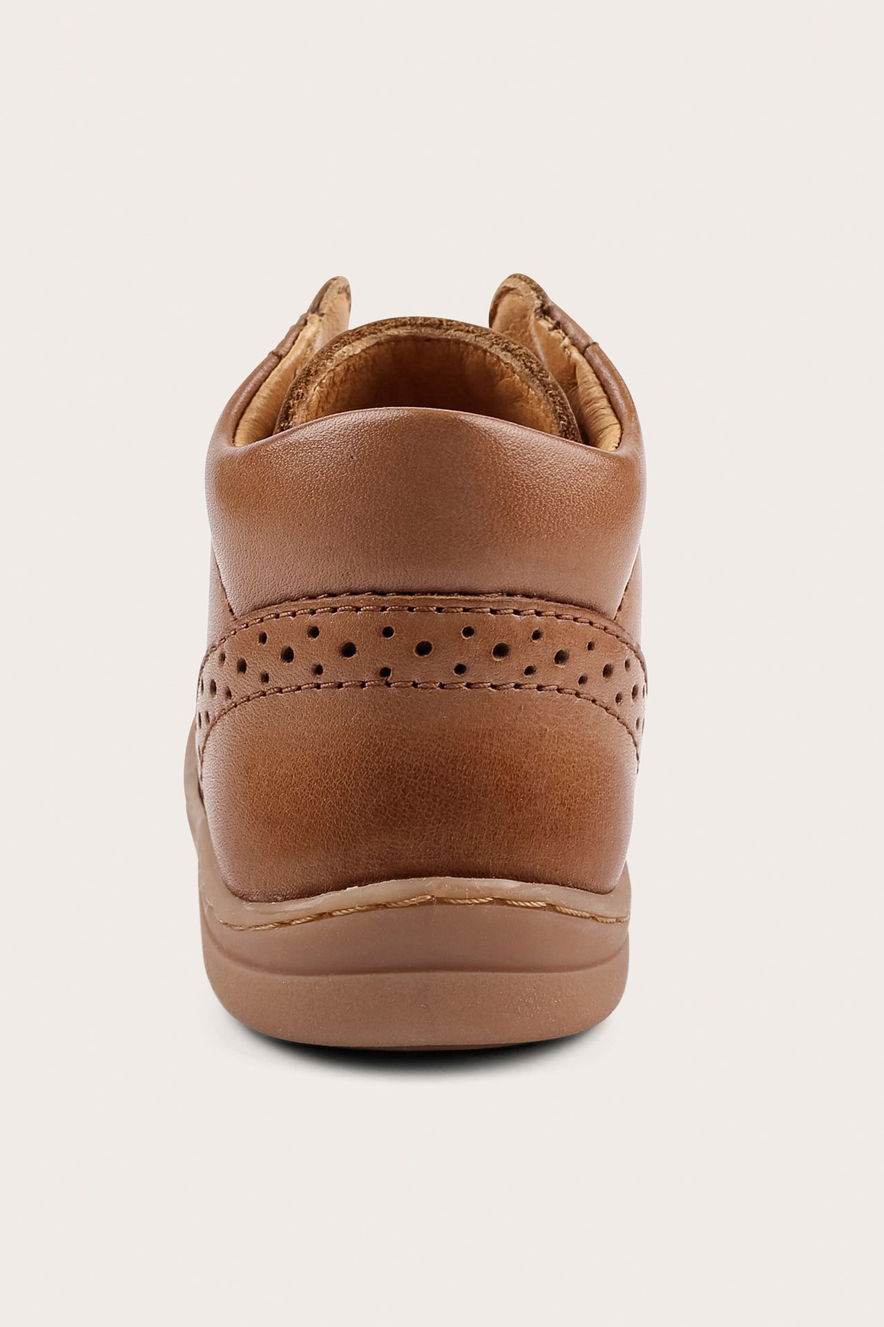 Bakifrån en brun läder lära-gå-sko för baby med texturerad yta och perforerade detaljer.