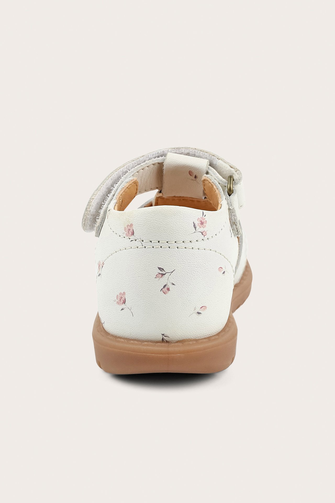 Bakifrån vit lädersandal för barn med små rosa blommor, kardborre och brun sula.