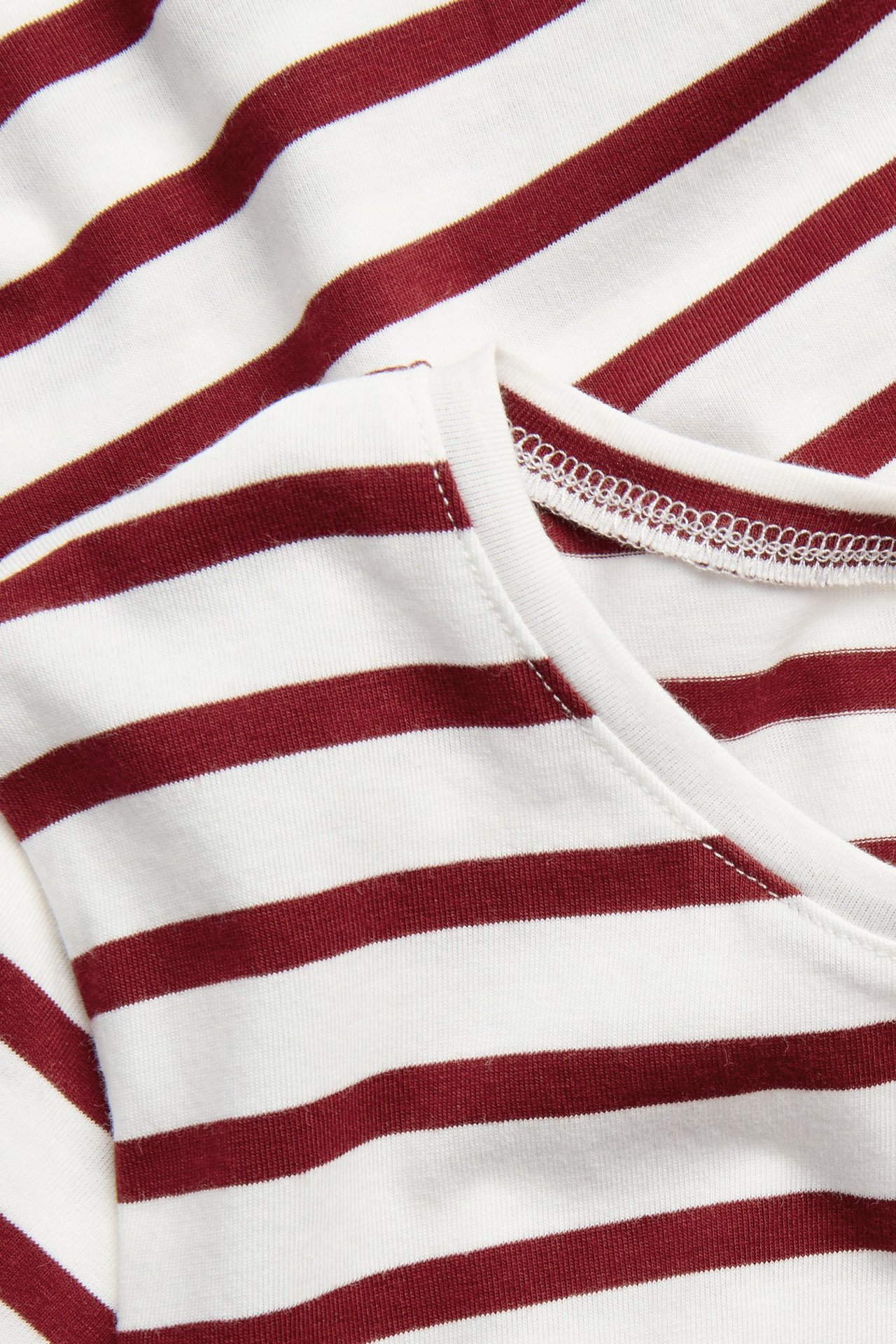 Zbliżenie na biało-bordowy prążkowany bawełniany top z krótkim rękawem i okrągłym dekoltem.