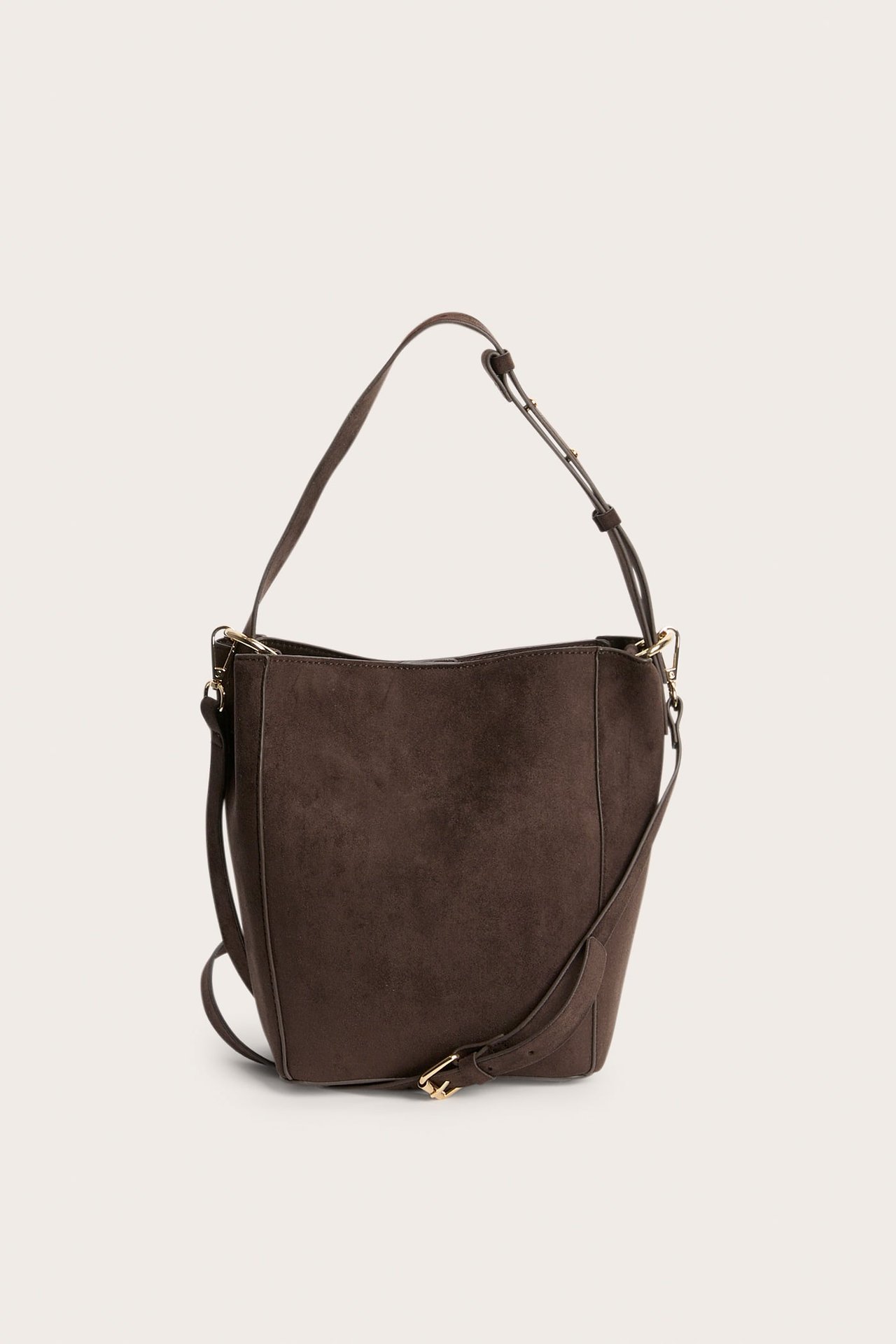 Frontvisning av en mørkebrun bøtteveske i imitert semsket skinn med justerbar reim og gullspenne.