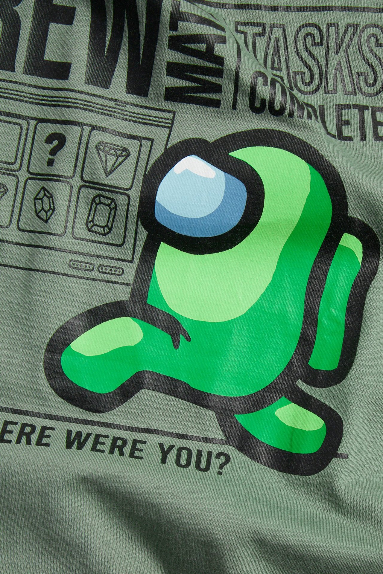 Nærbilde av en grønn T-skjorte i bomull med et livlig grønt Among Us-karaktertrykk foran.