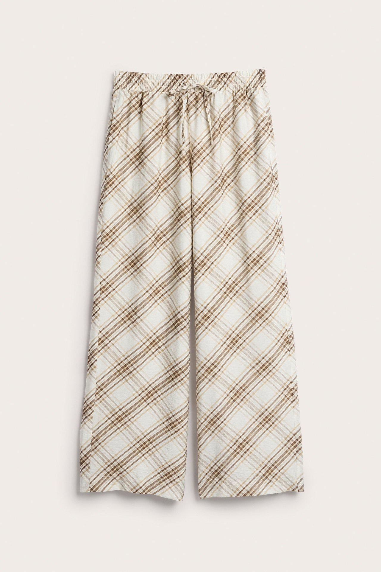 Widok z przodu: beżowe szerokie spodnie typu pull-on w brązową kratę, z elastycznym pasem i sznurkiem.