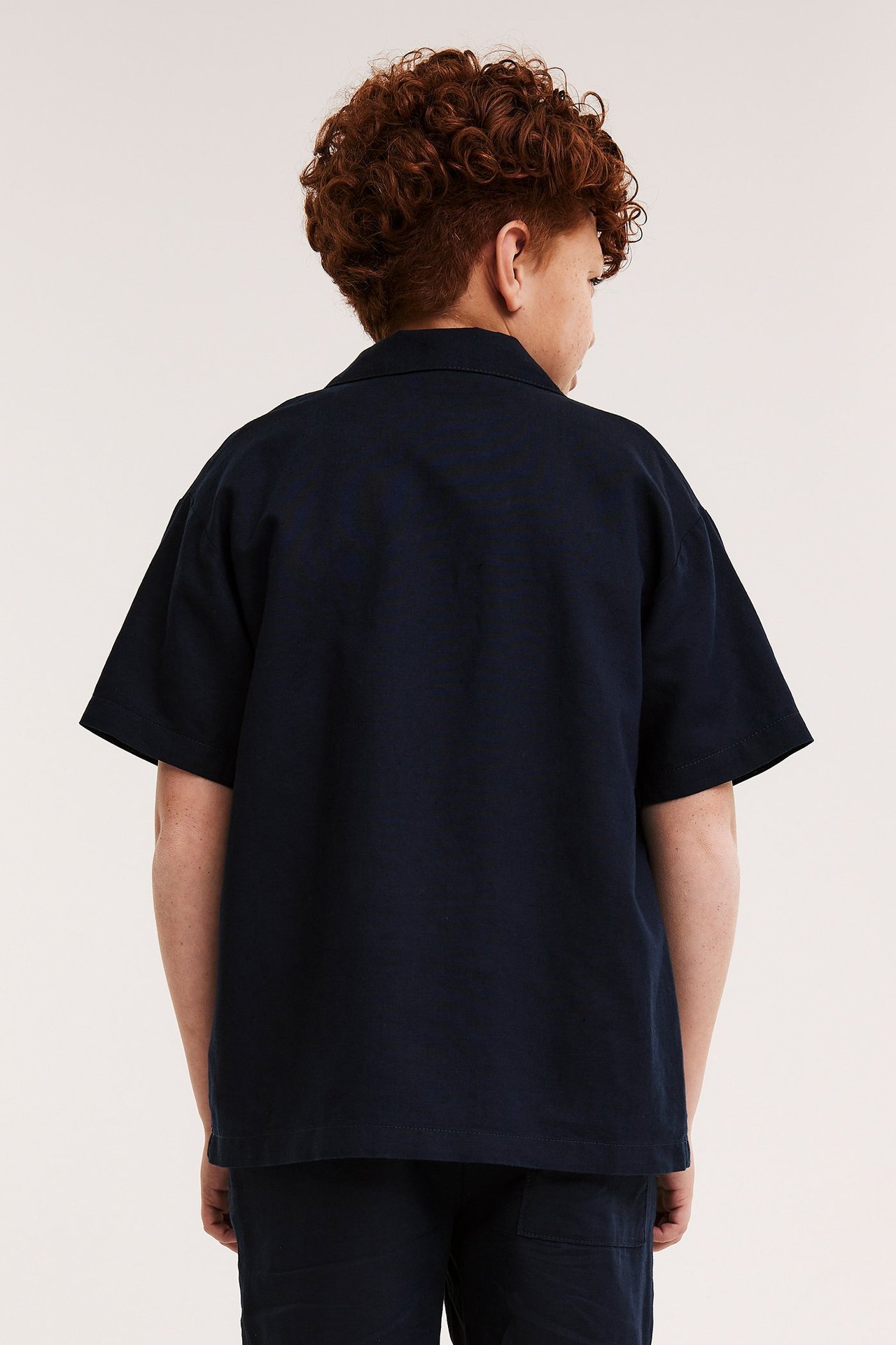 Widok od tyłu dziecka w granatowej koszuli z mieszanki lnu z krótkim rękawem i pasujących szortach.