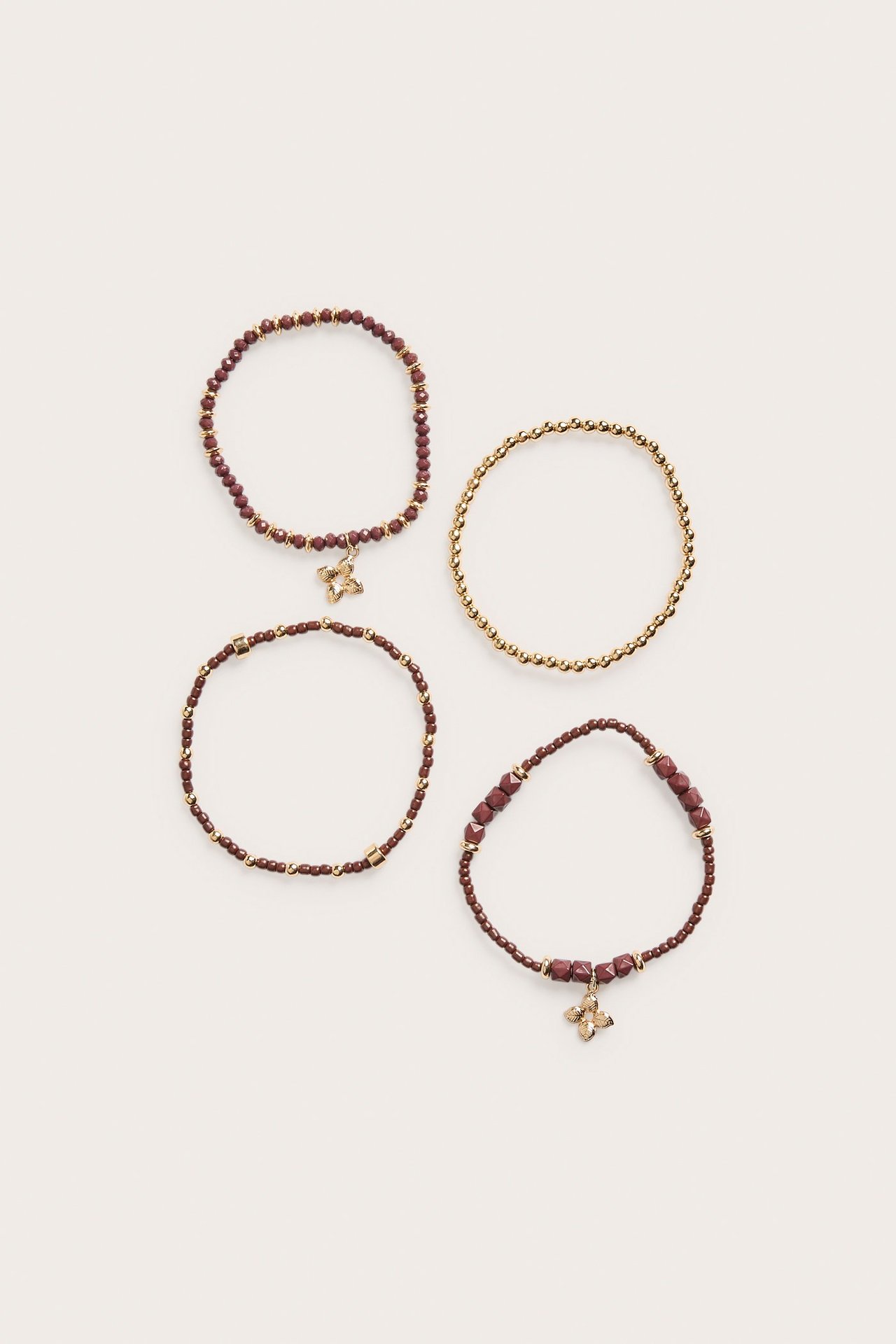 Widok z góry na cztery brązowo-złote elastyczne bransoletki z koralików, dwie z zawieszkami.