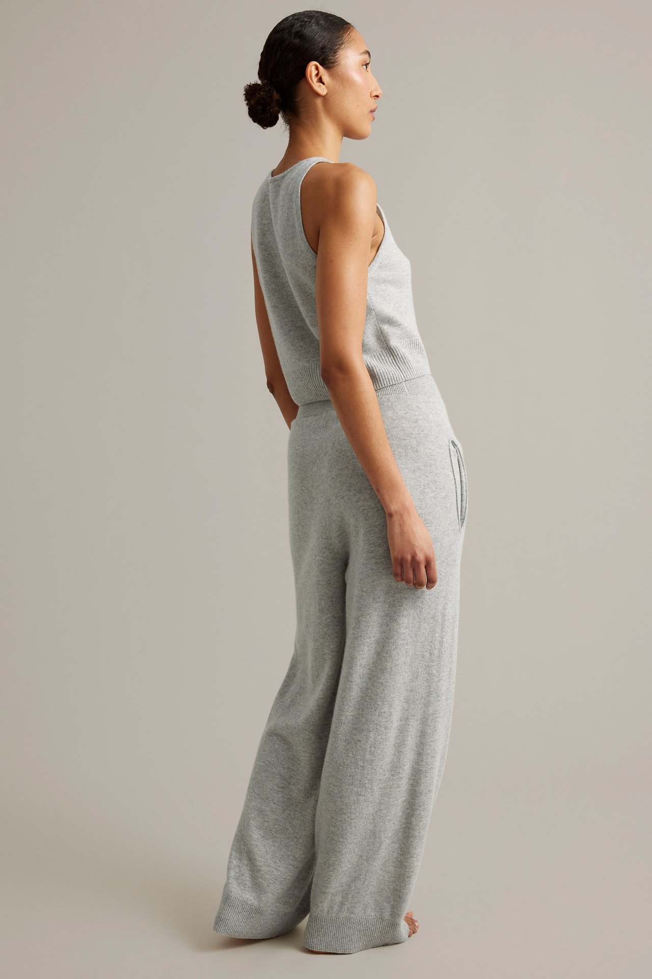 Naisen sivukuva yllään vaaleanharmaat meleeratut leveälahkeiset neulehousut villa/kashmirsekoitetta ja yhteensopiva toppi.