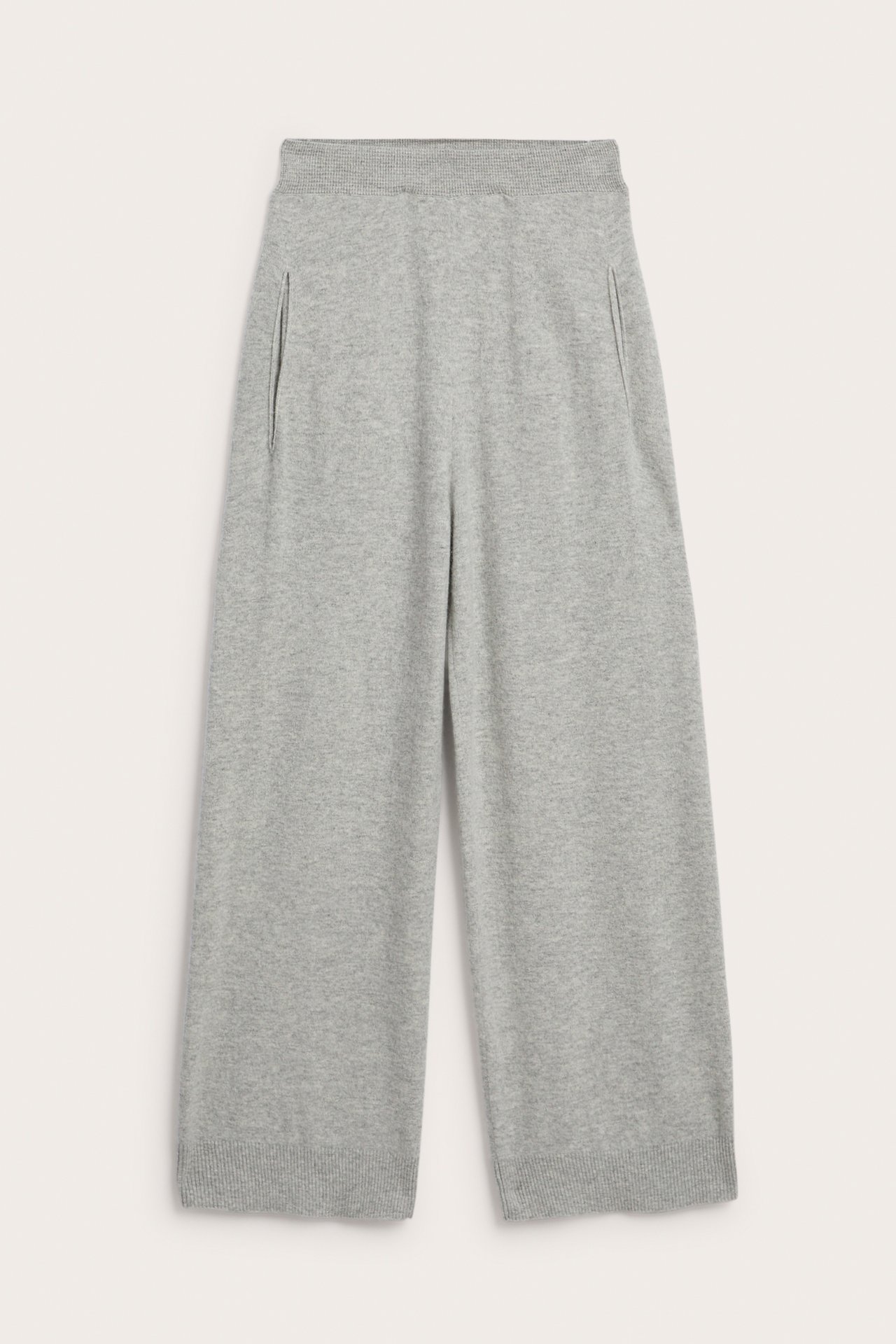 Framifrån, ljusgråmelerade stickade byxor i ull/kashmirblandning med vida ben, ribbad midja och sidfickor.
