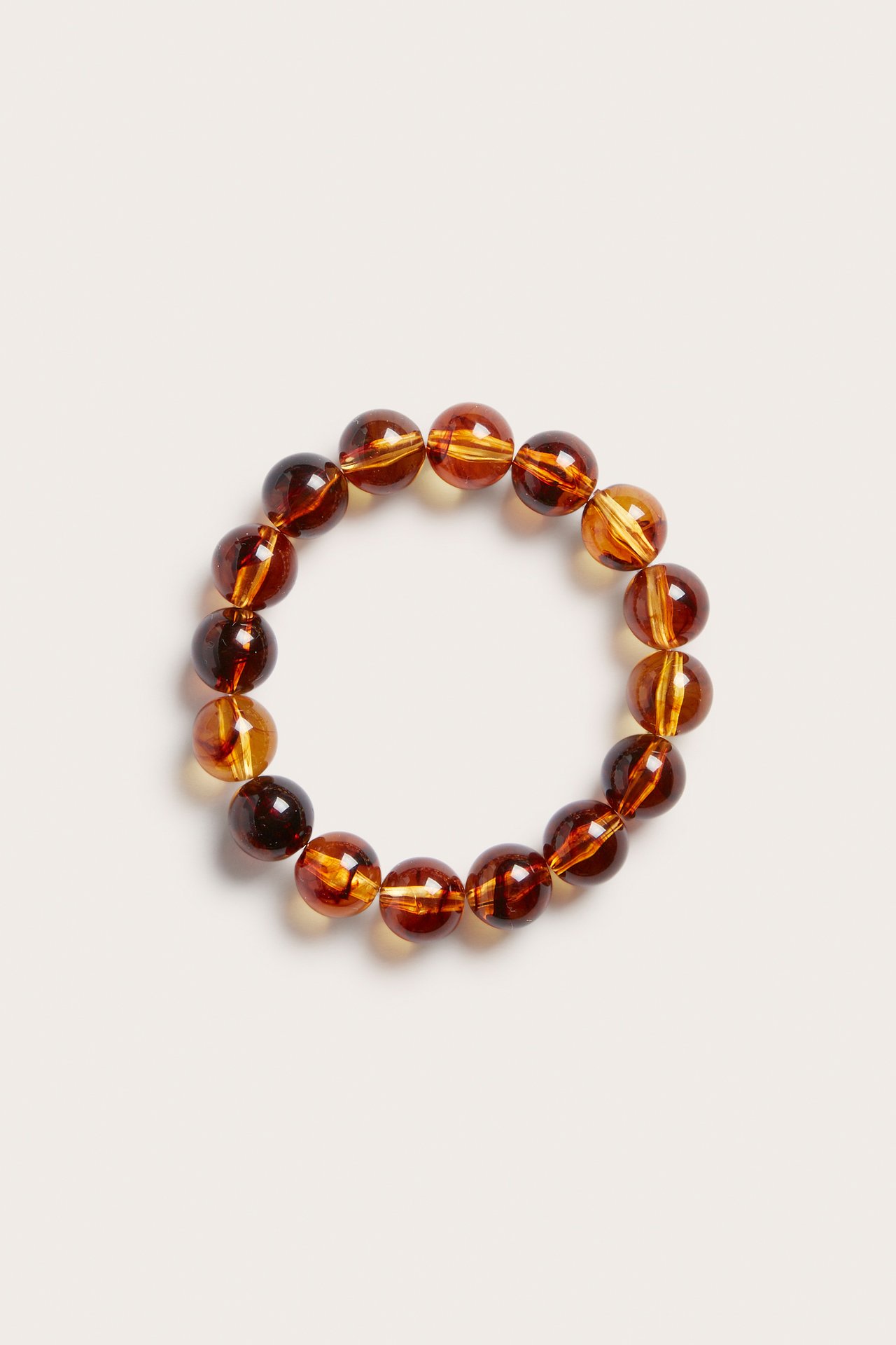 Övervy av ett elastiskt pärlarmband med runda, bärnstensfärgade plastpärlor.