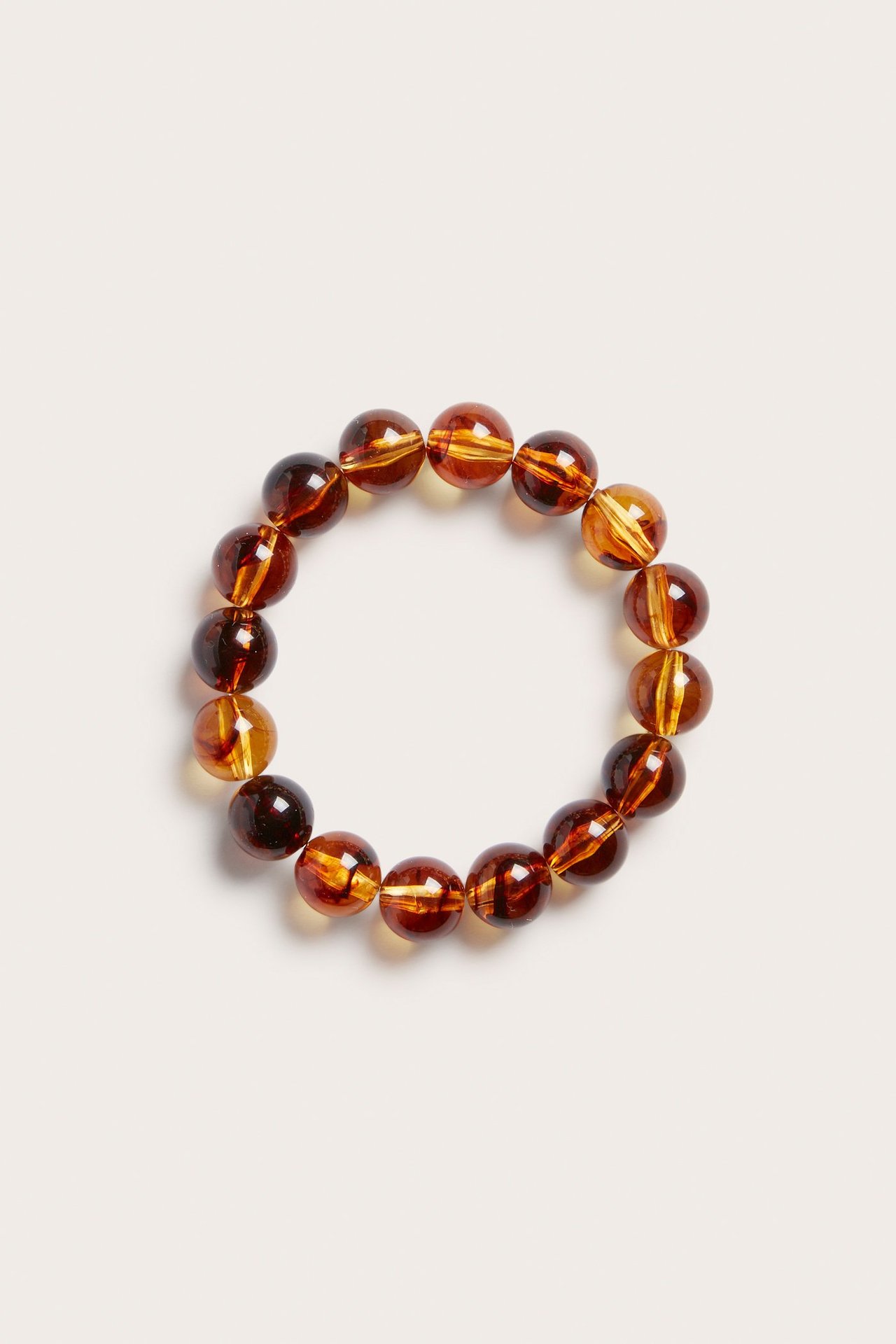 Topputsikt av et elastisk perlearmbånd med runde, ravfargede plastperler.