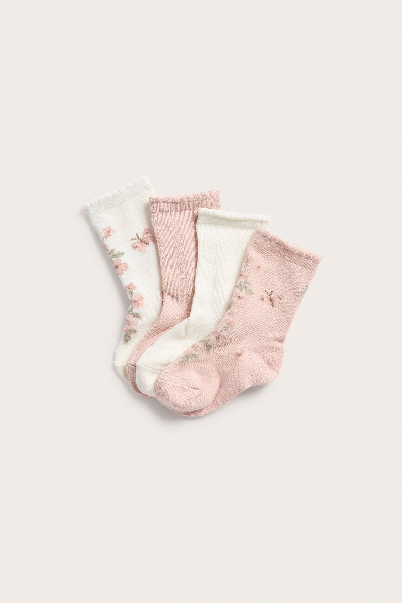 Toppvy av fyra baby-sockor: två blommiga (offwhite, rosa) och två mönstrade (rosa, offwhite).