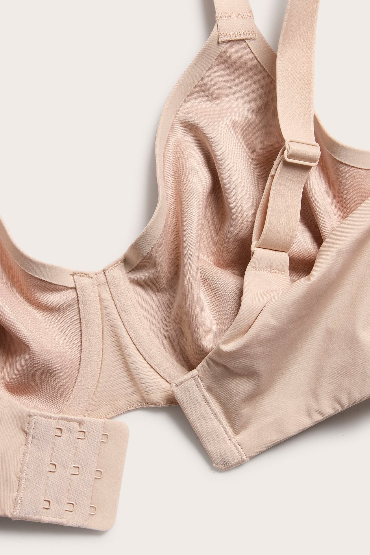 Närbild på en ovadderad ljusrosa minimizer-bh med justerbara axelband och hysk- och hakknäppning.