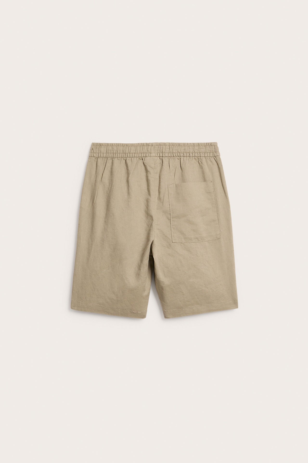 Takakuva beigeistä pellavasekoiteshortseista, joissa joustava vyötärö ja yksi takatasku.
