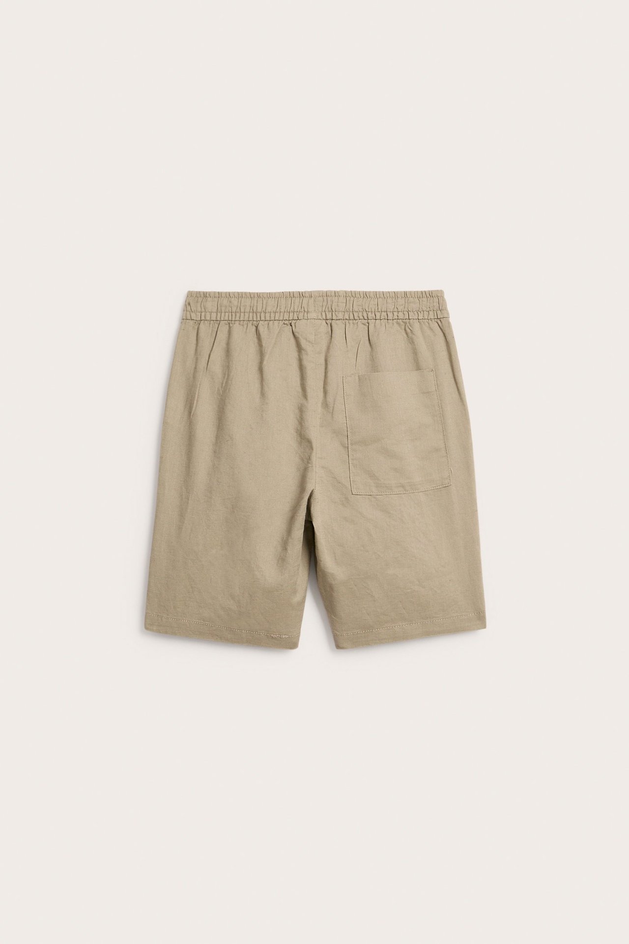 Takakuva beigeistä pellavasekoiteshortseista, joissa joustava vyötärö ja yksi takatasku.