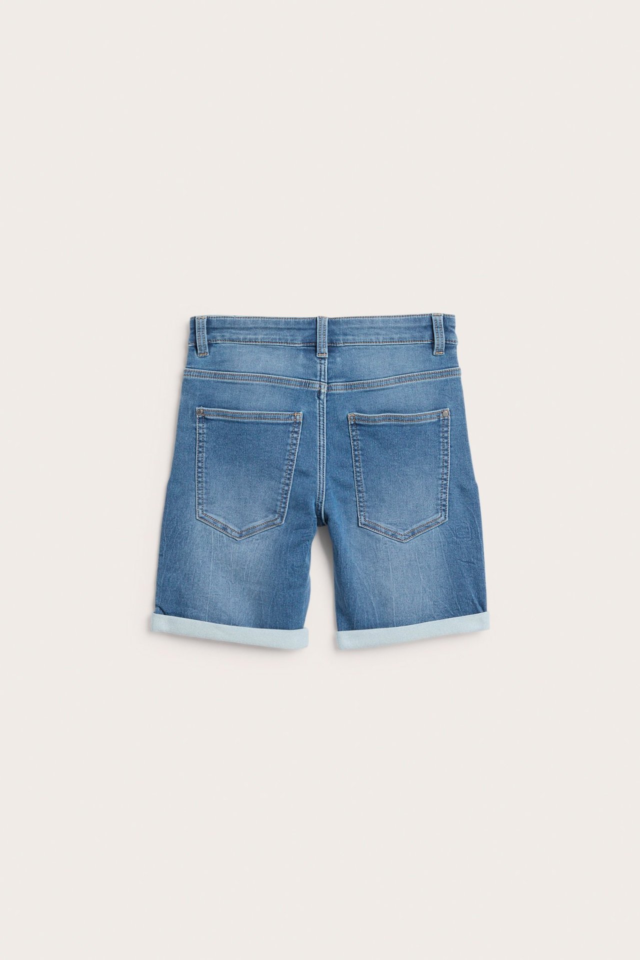Tylny widok jasnoniebieskich elastycznych szortów jeansowych dla dzieci, z podwiniętymi nogawkami i tylnymi kieszeniami.