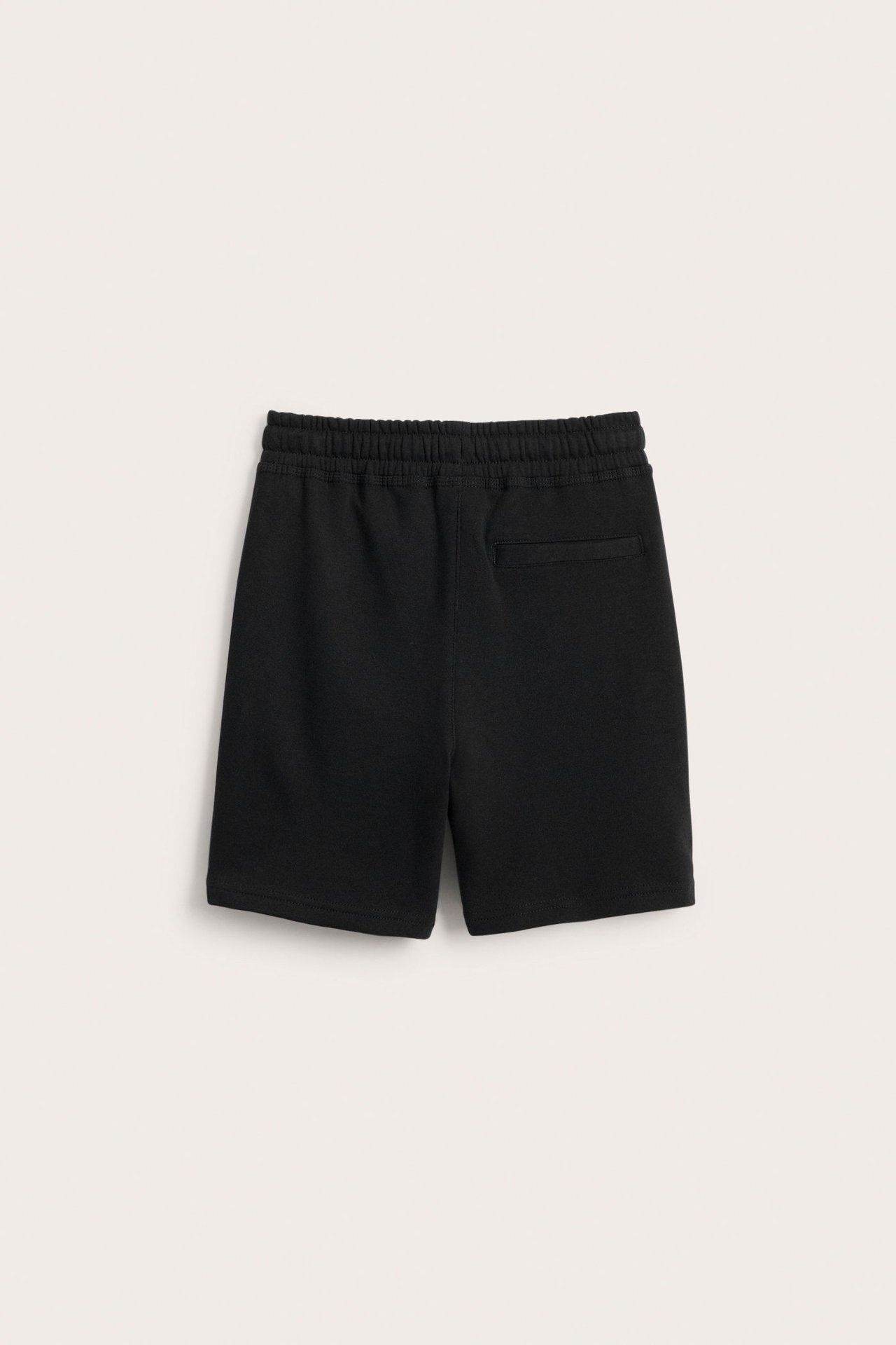 Bakifrån av svarta sweatshorts i bomullstrikå med resårlinning och en bakficka.