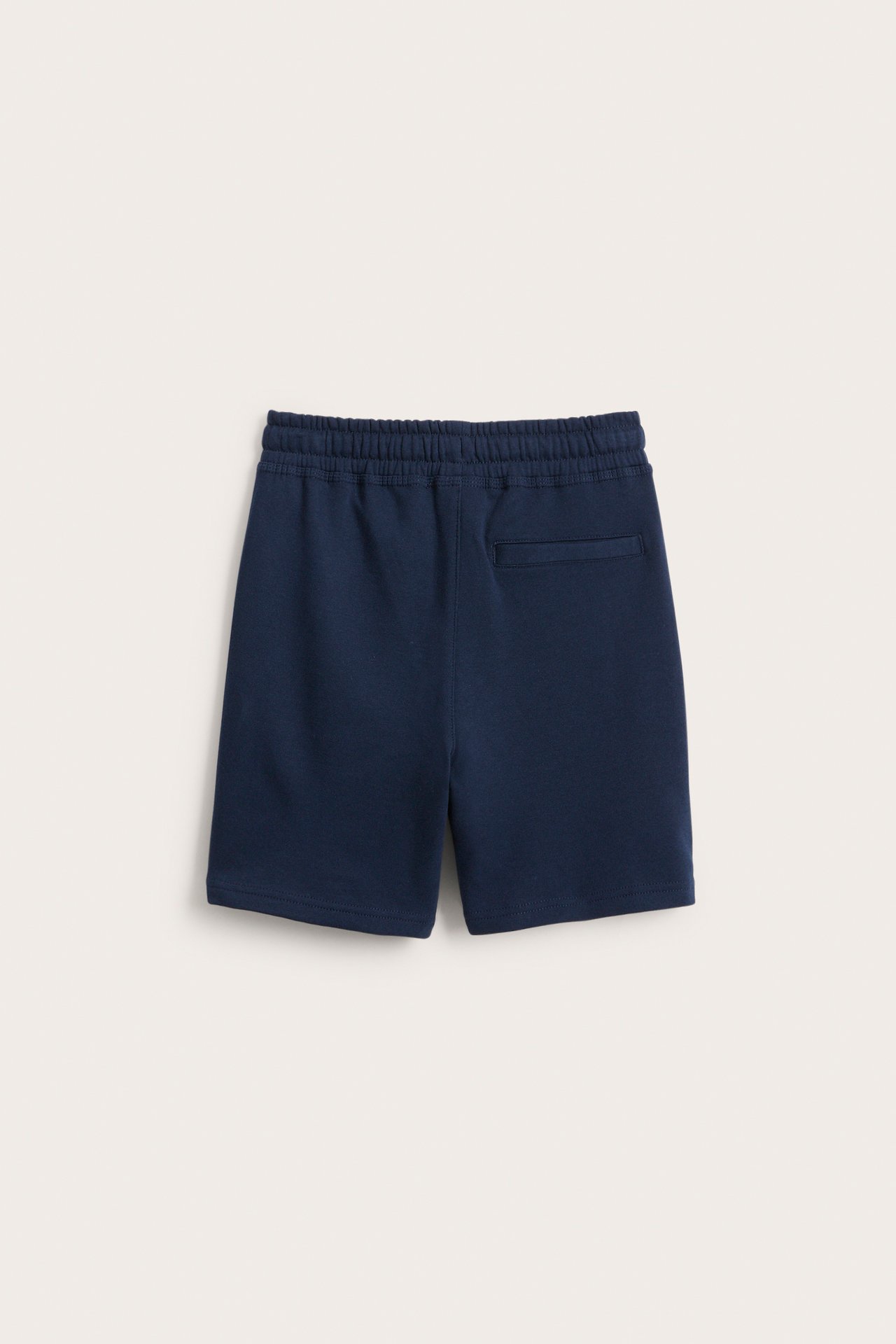 Bakifrån: mörkblå mjukisshorts i bomullstrikå med elastisk midja och en bakficka.