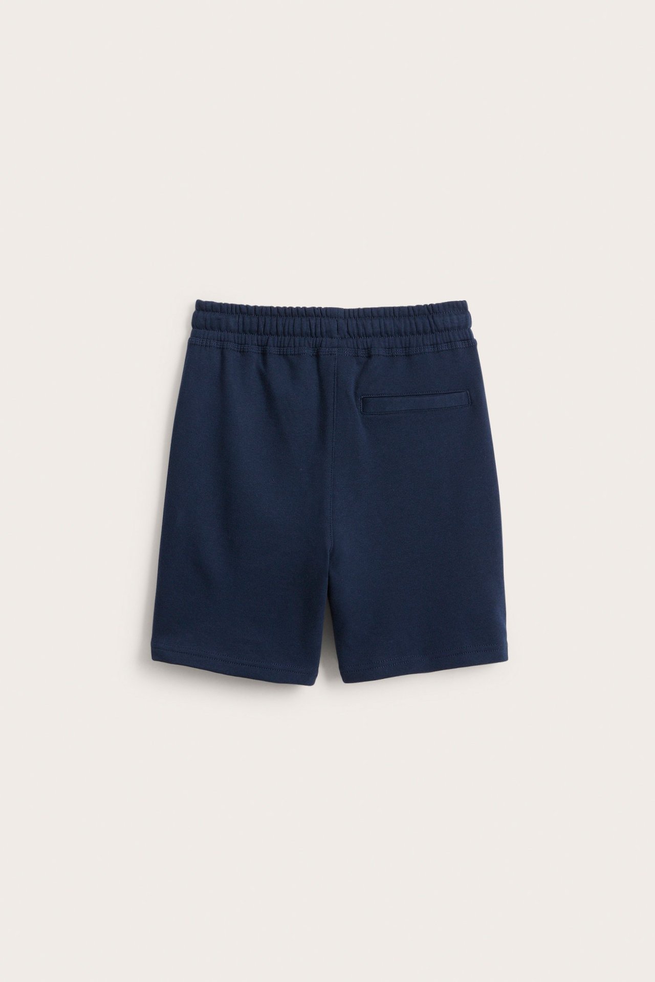 Takakuva tummansinisistä puuvillaneuleisista college-shortseista, joissa on joustava vyötärö ja takatasku.