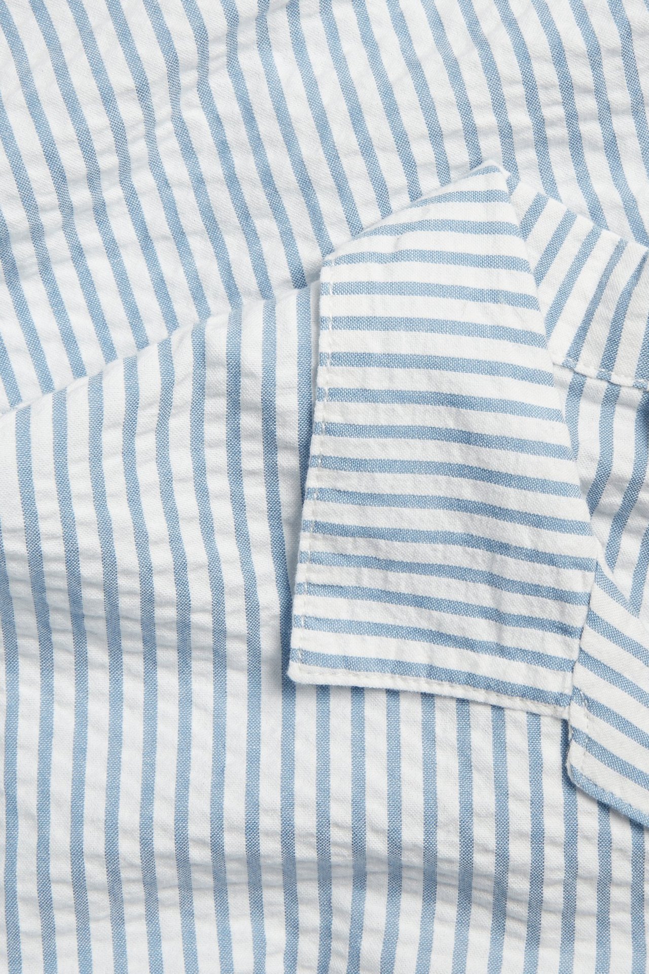 Närbild av en blåvitrandig kortärmad skjorta i texturerad bäckebölja-bomull.