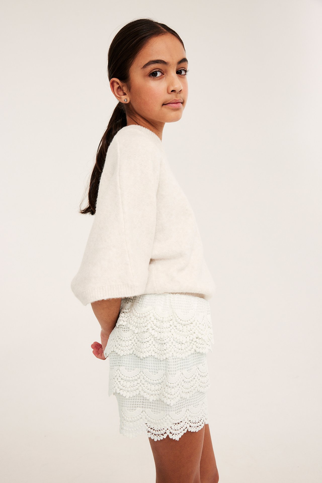 Sidebilde: barn i kremhvite blonde-shorts med elastisk midje, og en myk kremhvit genser.