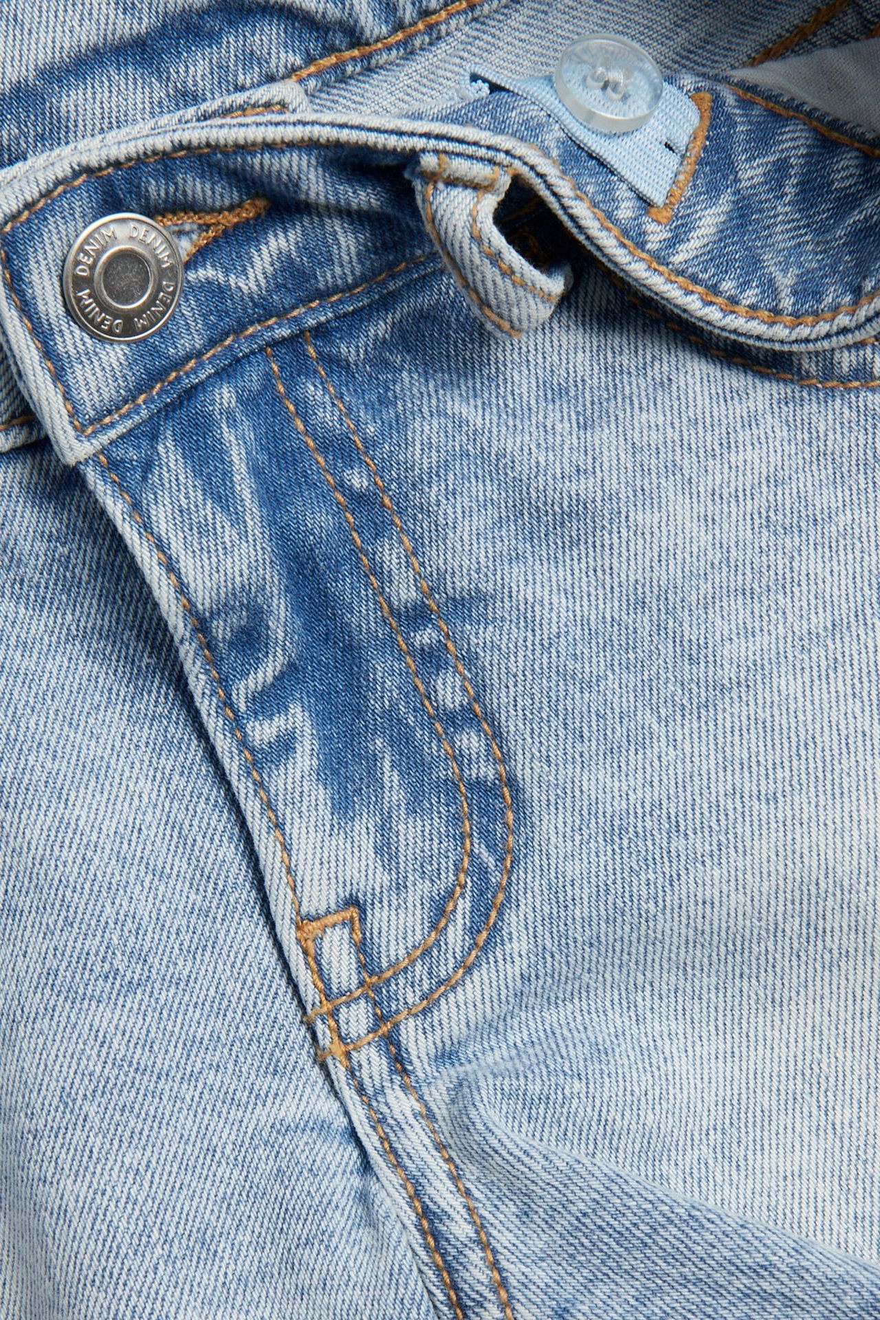 Zbliżenie na jasnoniebieskie szorty jeansowe z metalowym guzikiem, widocznym zamkiem i przednią kieszenią.