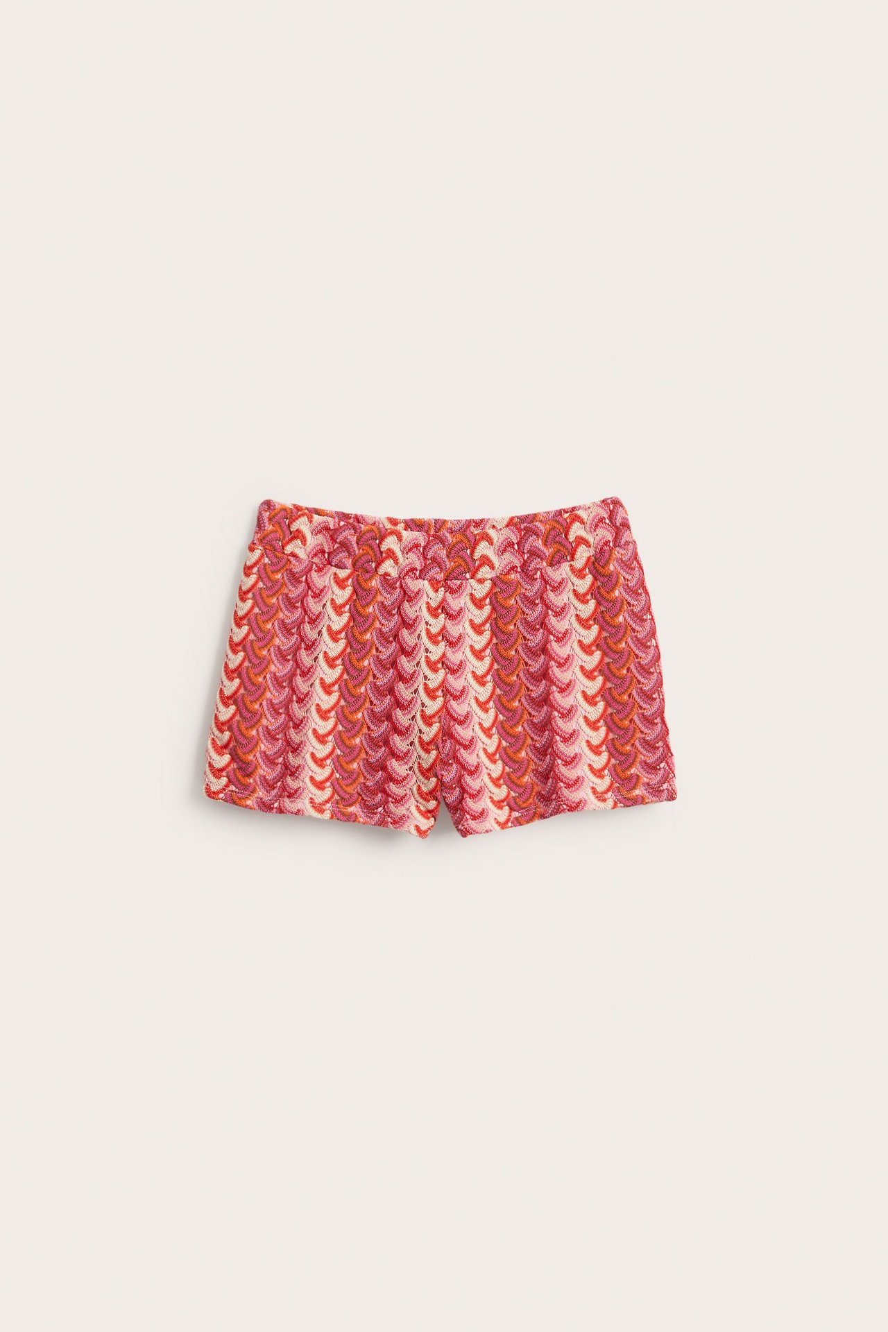Widok z przodu różowo-czerwonych krótkich szortów z szydełkowanym wzorem i gumką w pasie.