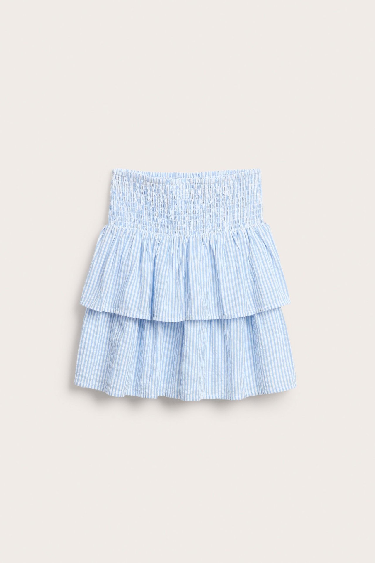 Framifrån, en randig volangkjol för barn i ljusblått och vitt med smockad midja.