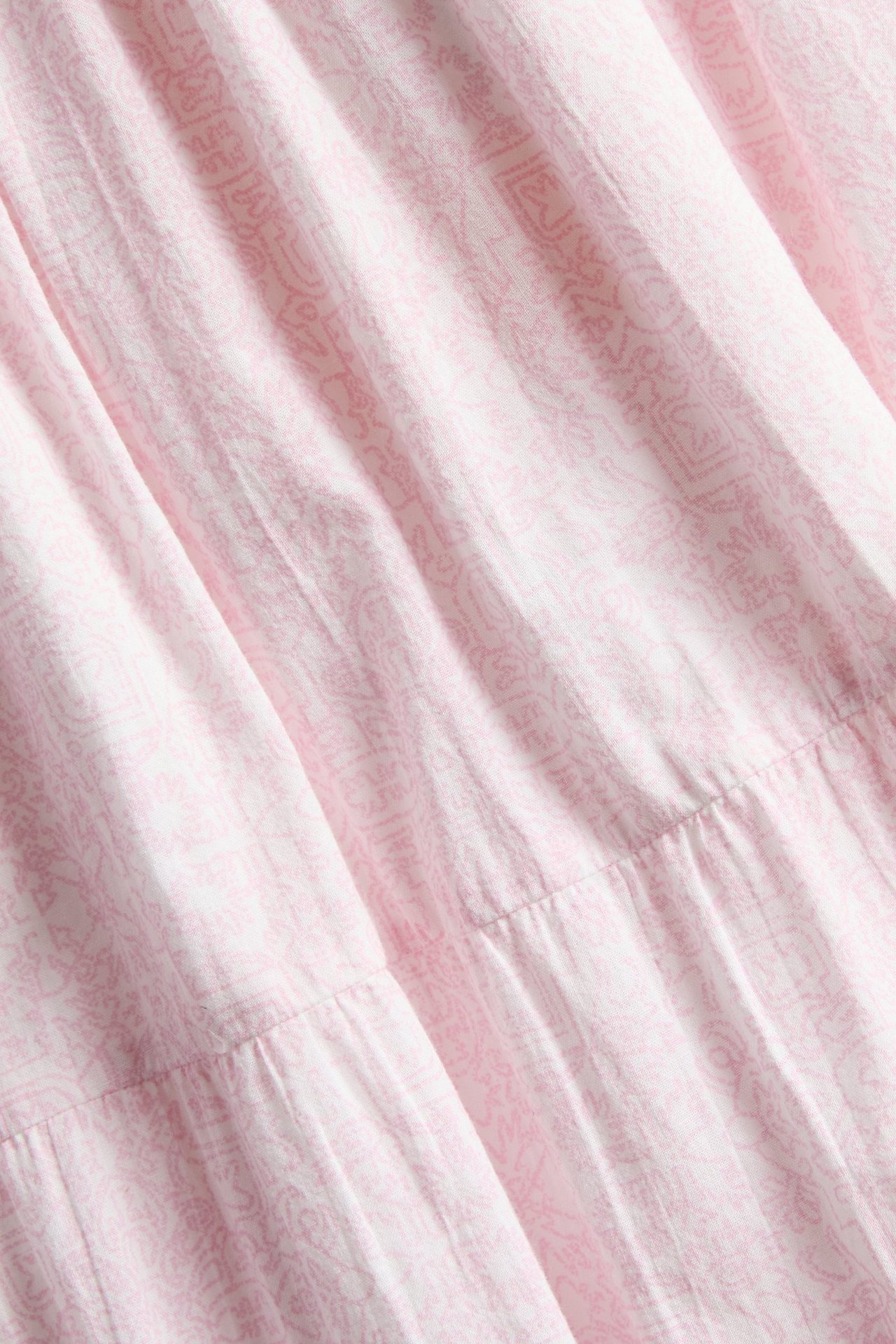 Zbliżenie na różową, wzorzystą bawełnianą spódnicę maxi z abstrakcyjnym nadrukiem i warstwowym fasonem.