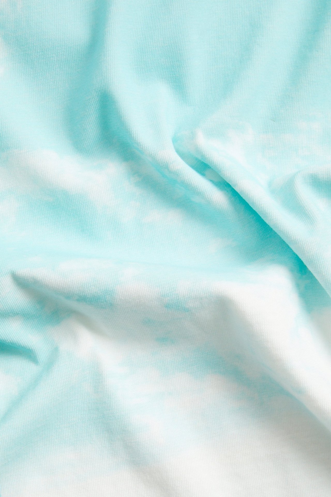 Lähikuva pehmeästä luonnonvalkoisesta ja vaaleansinisestä puuvilla-t-paitakankaasta, jossa on pilvikuvio.