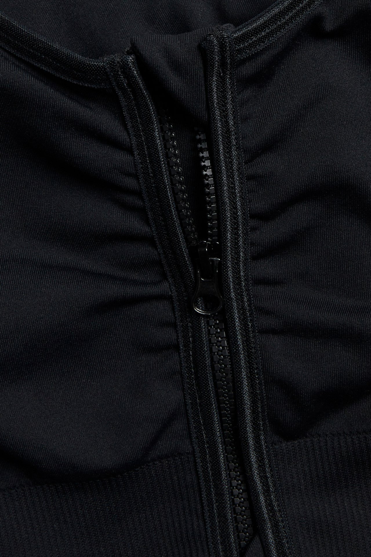 Nærbilde av svart sømløs BH med glidelås og samlet stoff.