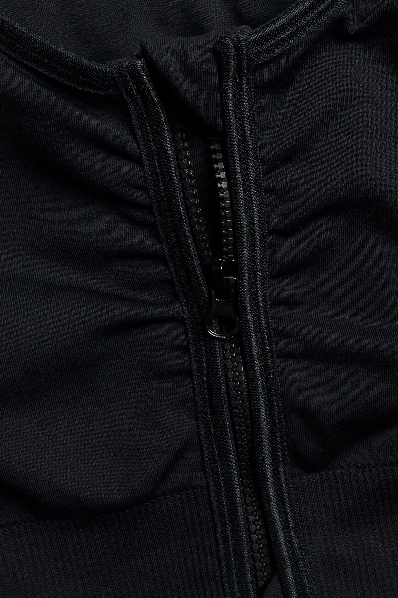 Nærbilde av svart sømløs BH med glidelås og samlet stoff.