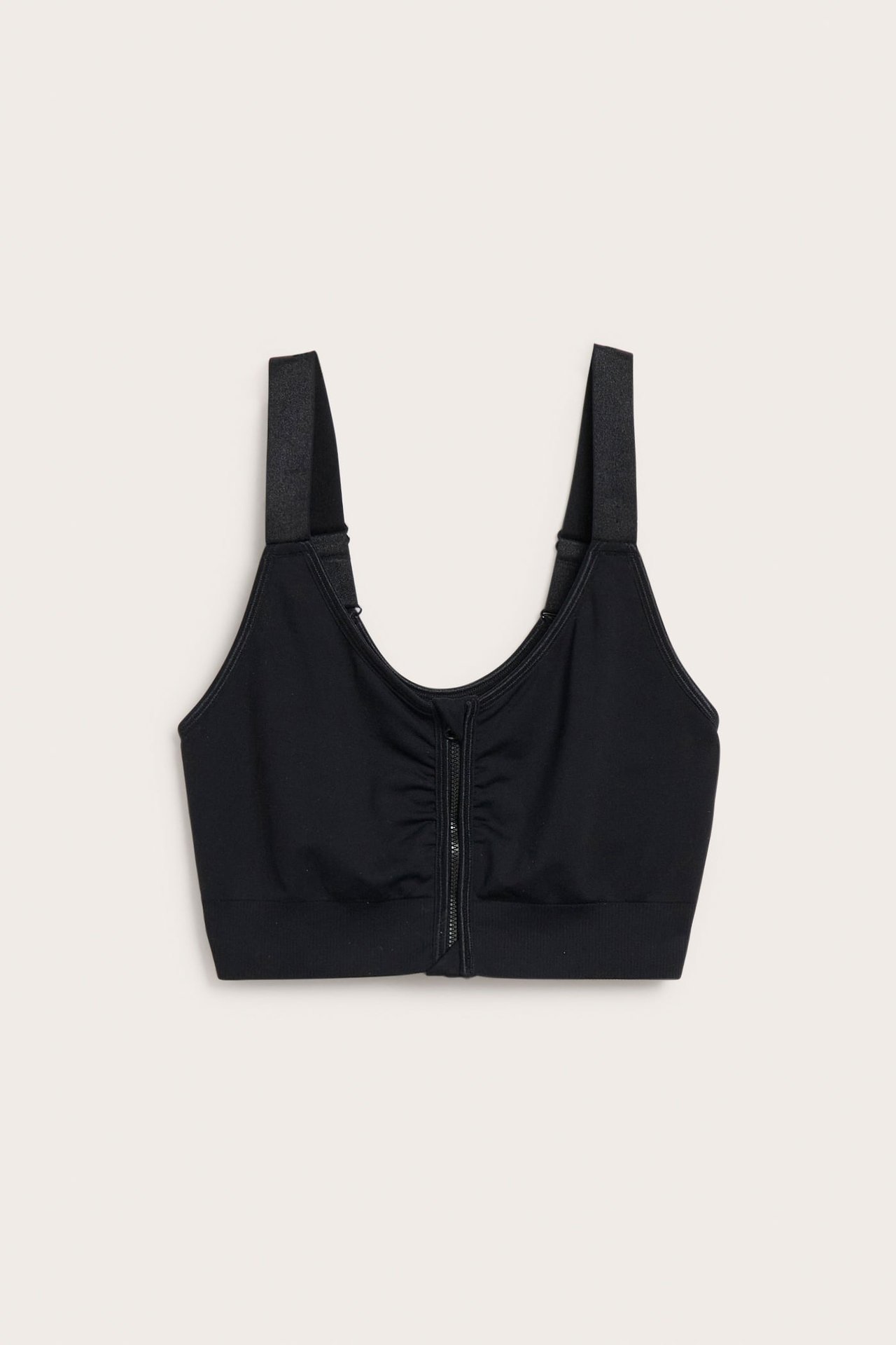 Frontvisning av en svart sømløs BH med brede stropper og glidelås med hektelås foran.