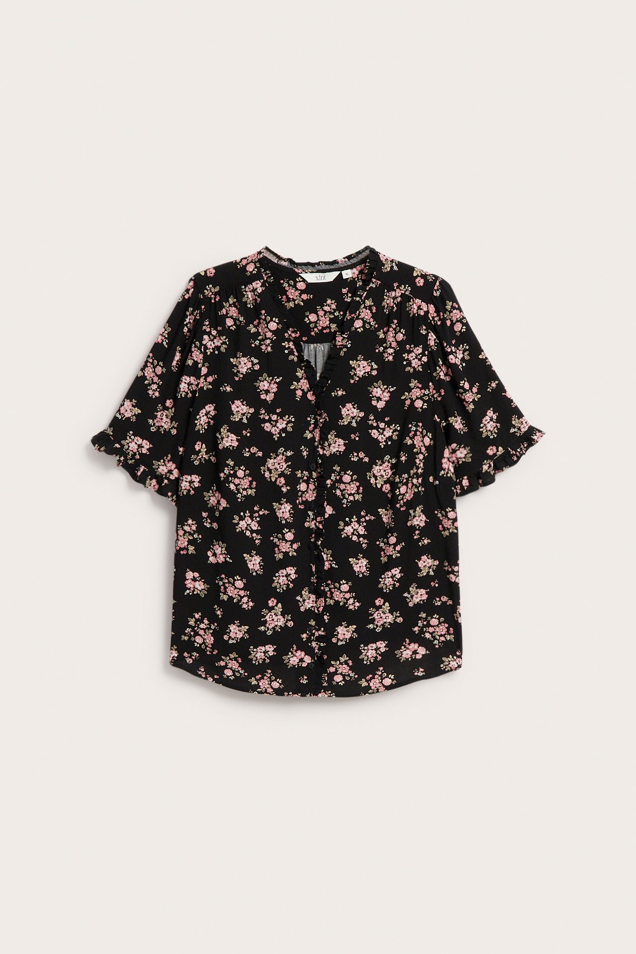 Frontvisning: Svart blomstret viskosebluse med volang V-hals, korte volangermer og tildekkede knapper.