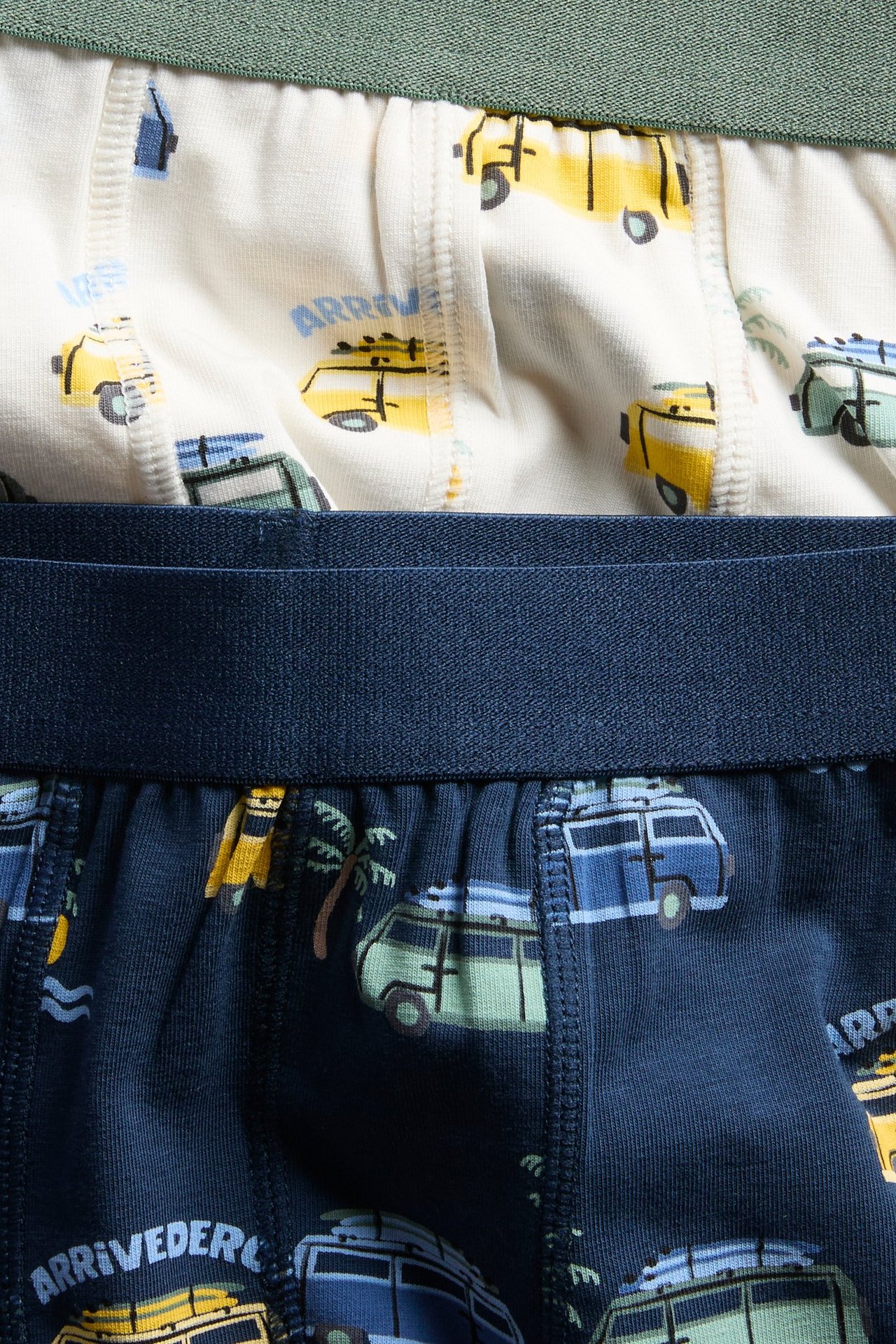 Zbliżenie na ciemnoniebieskie dziecięce bokserki we wzory z pojazdami i kremowe bokserki we wzory.