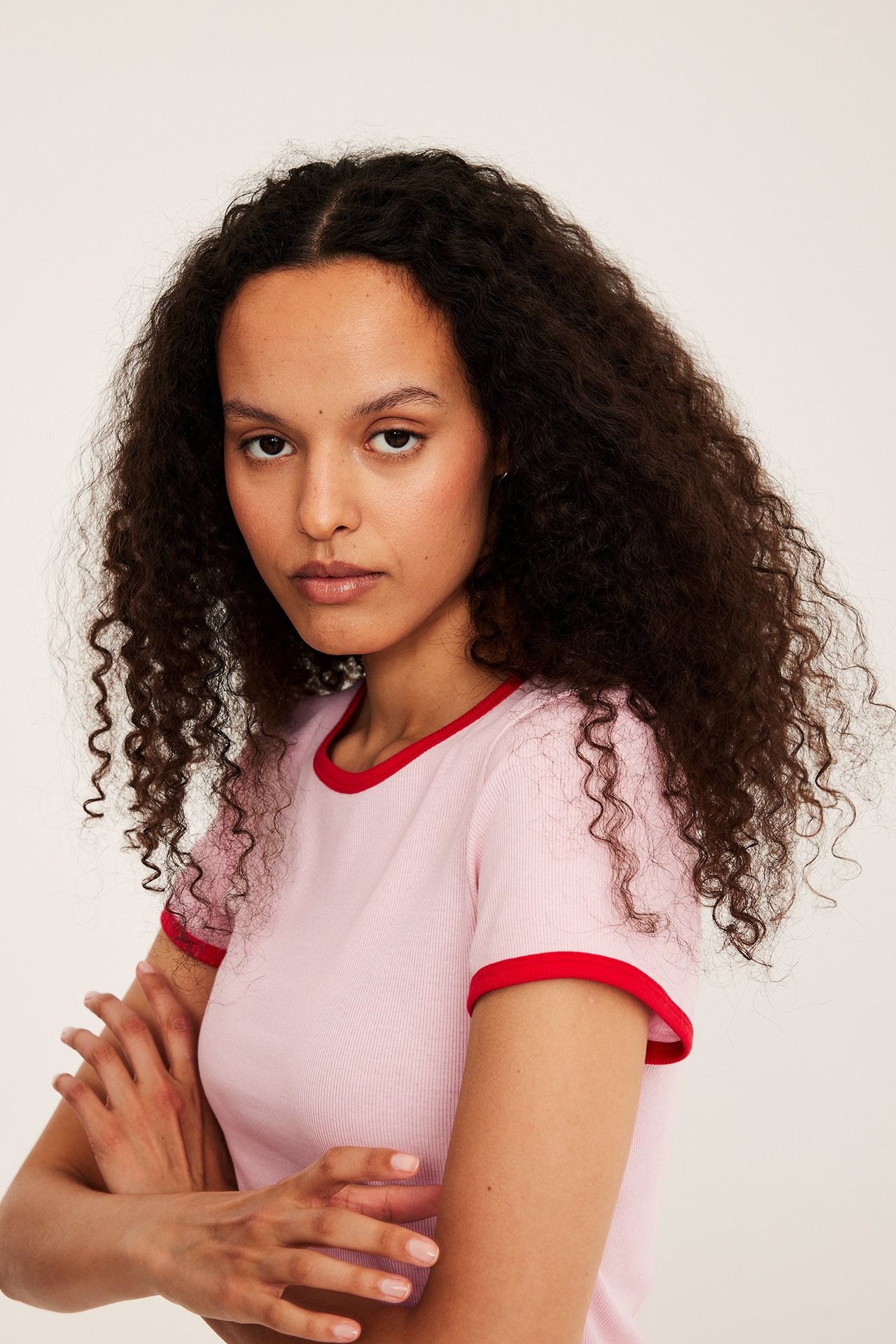Edestäpäin: nainen istuvassa vaaleanpunaisessa ribbipaidassa punaisilla kontrastireunoilla.