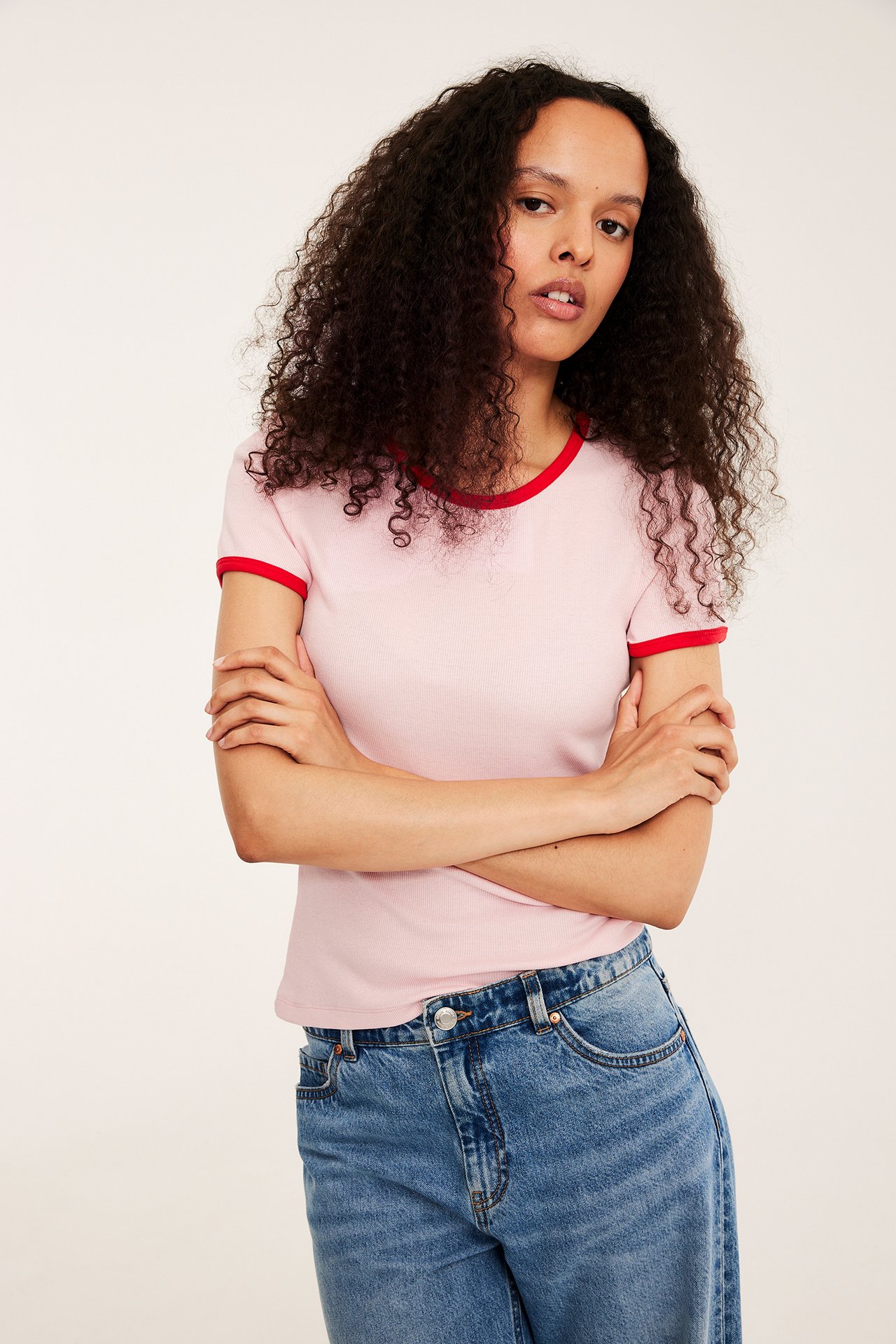 Edestäpäin: nainen yllään vaaleanpunainen ribbitoppi punaisilla reunoilla ja siniset farkut.