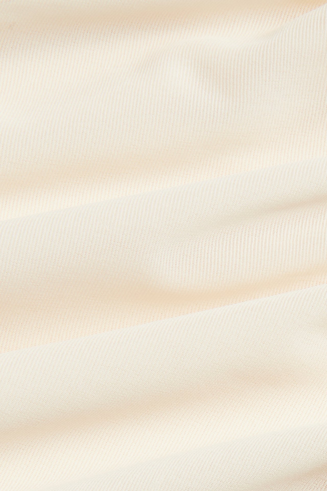 Närbild av offwhite skir topptyg med subtil textur och mjuka veck.