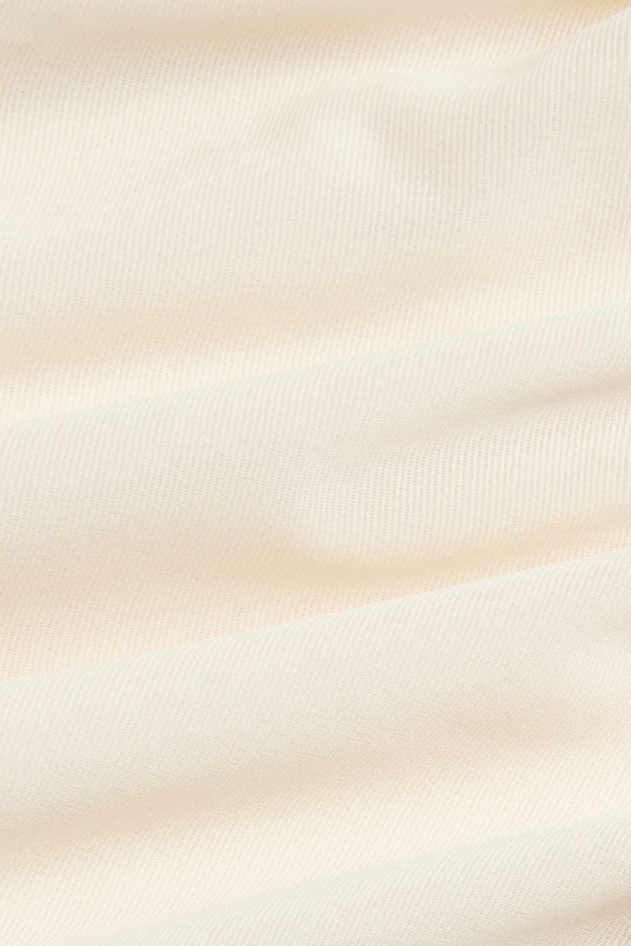 Zbliżenie na przezroczysty materiał topu w kolorze złamanej bieli z delikatną teksturą.