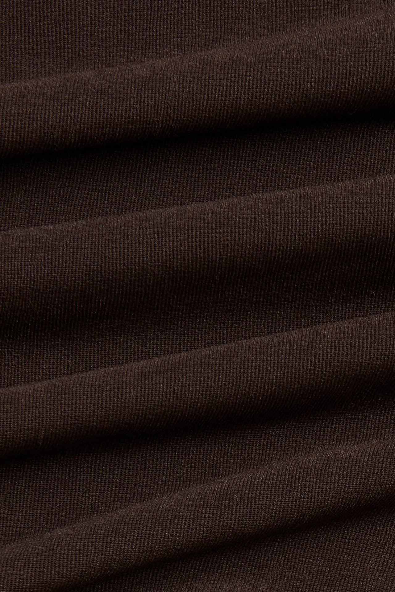 Zbliżenie na ciemnobrązowy, jednolity materiał prześwitującego topu, prezentujący subtelną, prążkowaną teksturę.