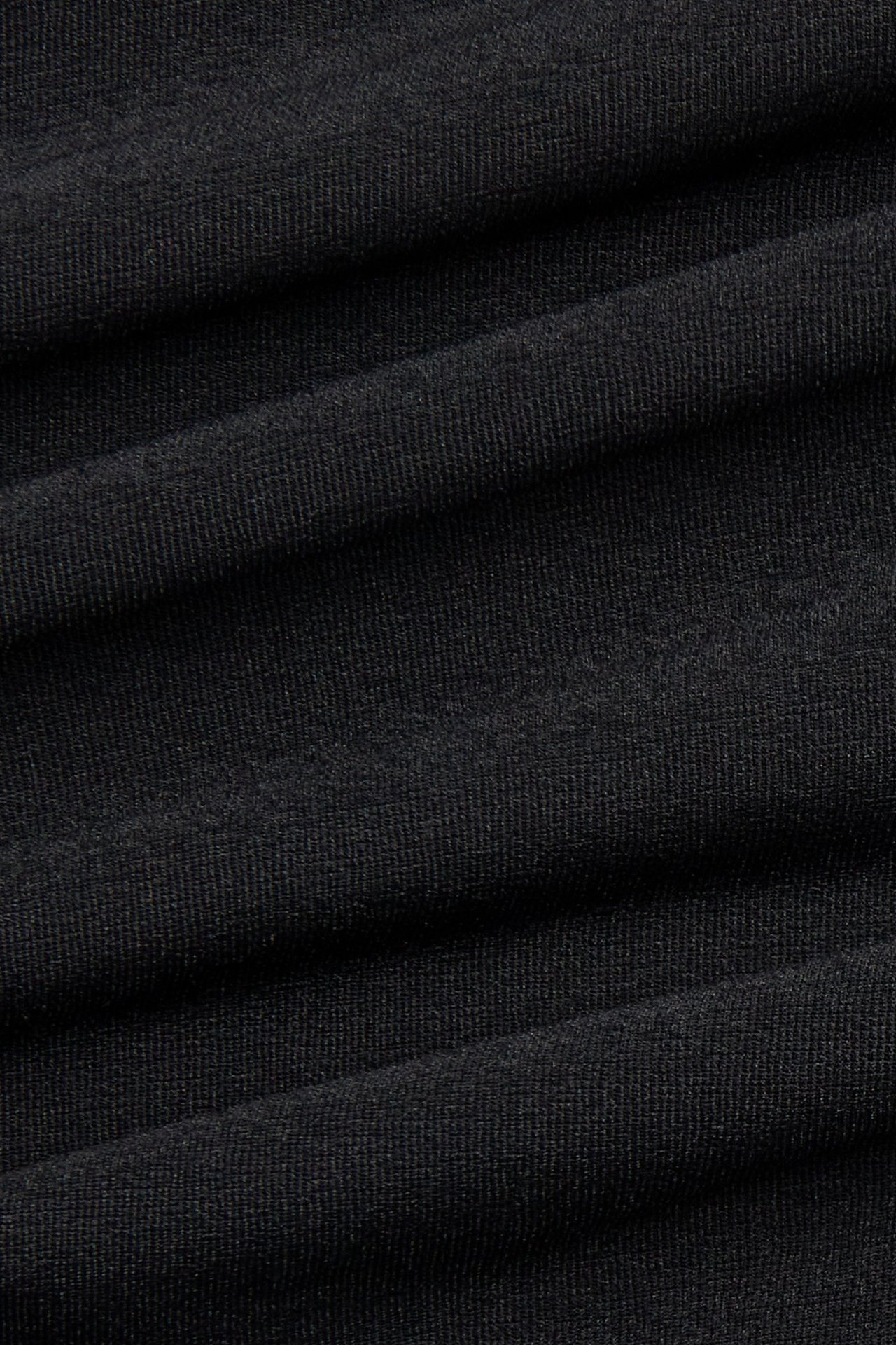 Zbliżenie na czarny materiał z widoczną teksturą i delikatnymi fałdami.