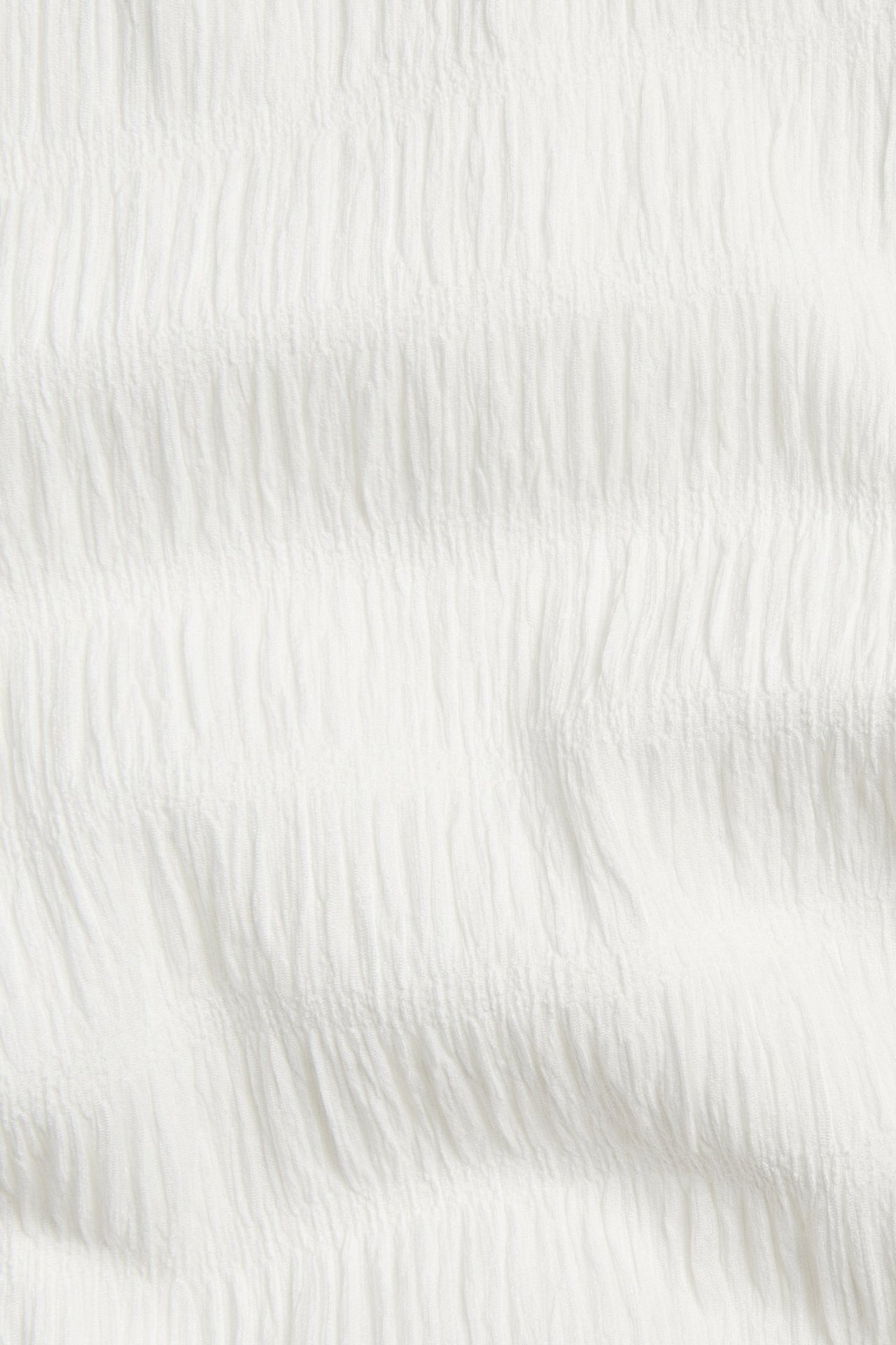 Zbliżenie na ekru, strukturalną tkaninę poliestrowo-elastanową z delikatnym pionowym marszczonym wzorem.