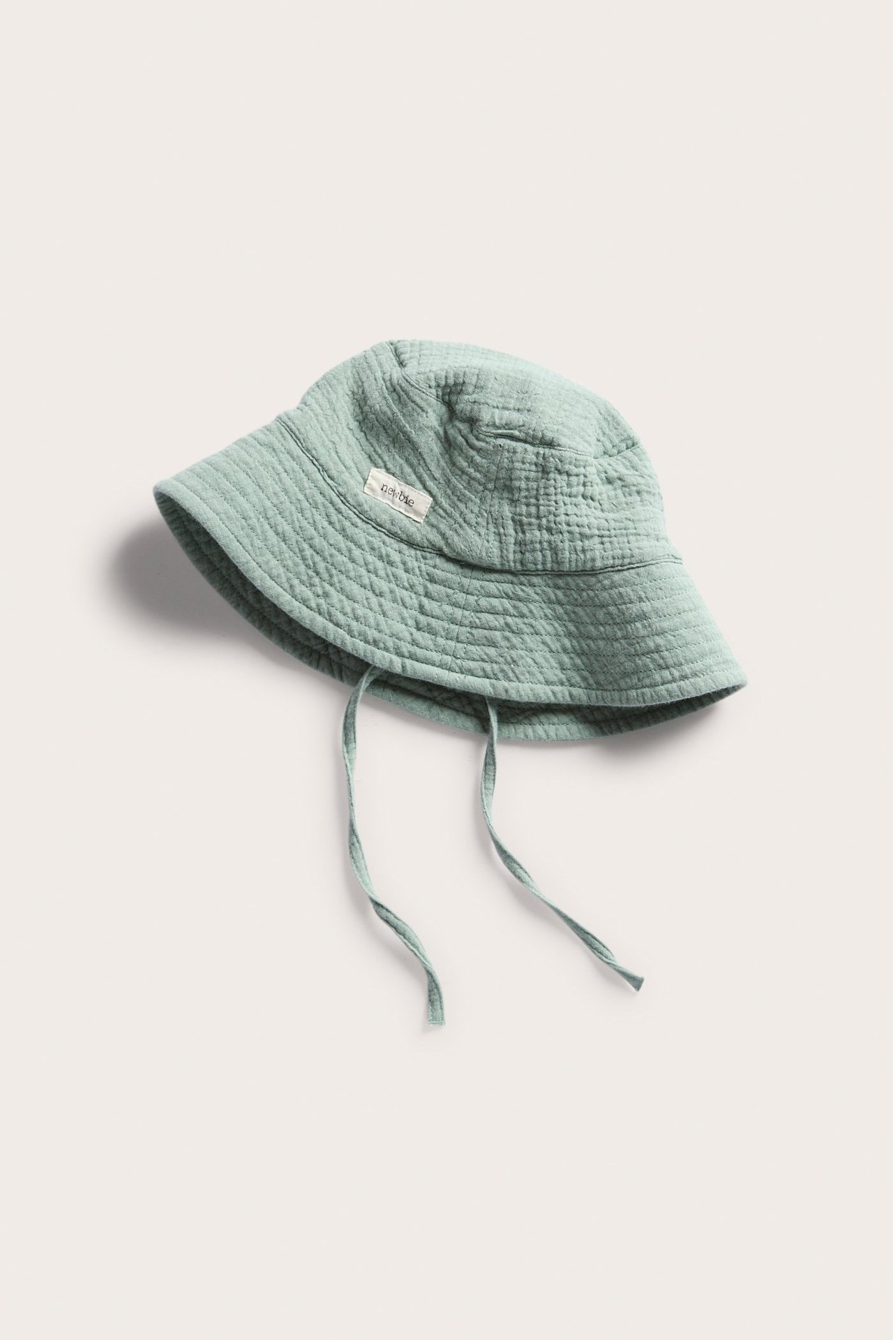 Widok z góry na zielony kapelusz słoneczny dla niemowląt z troczkami, z miękkiej pikowanej tkaniny.