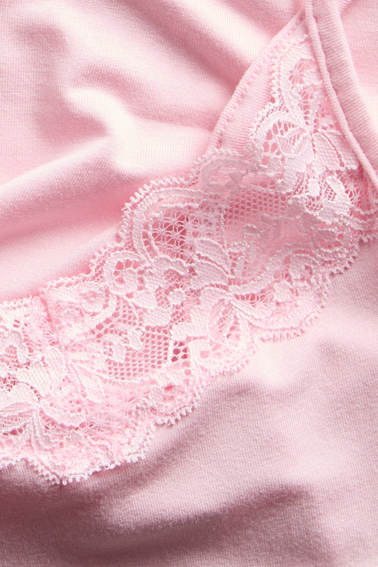Lähikuva vaaleanpunaisesta topista, jossa on vaaleanpunainen pitsireunus pääntiessä.