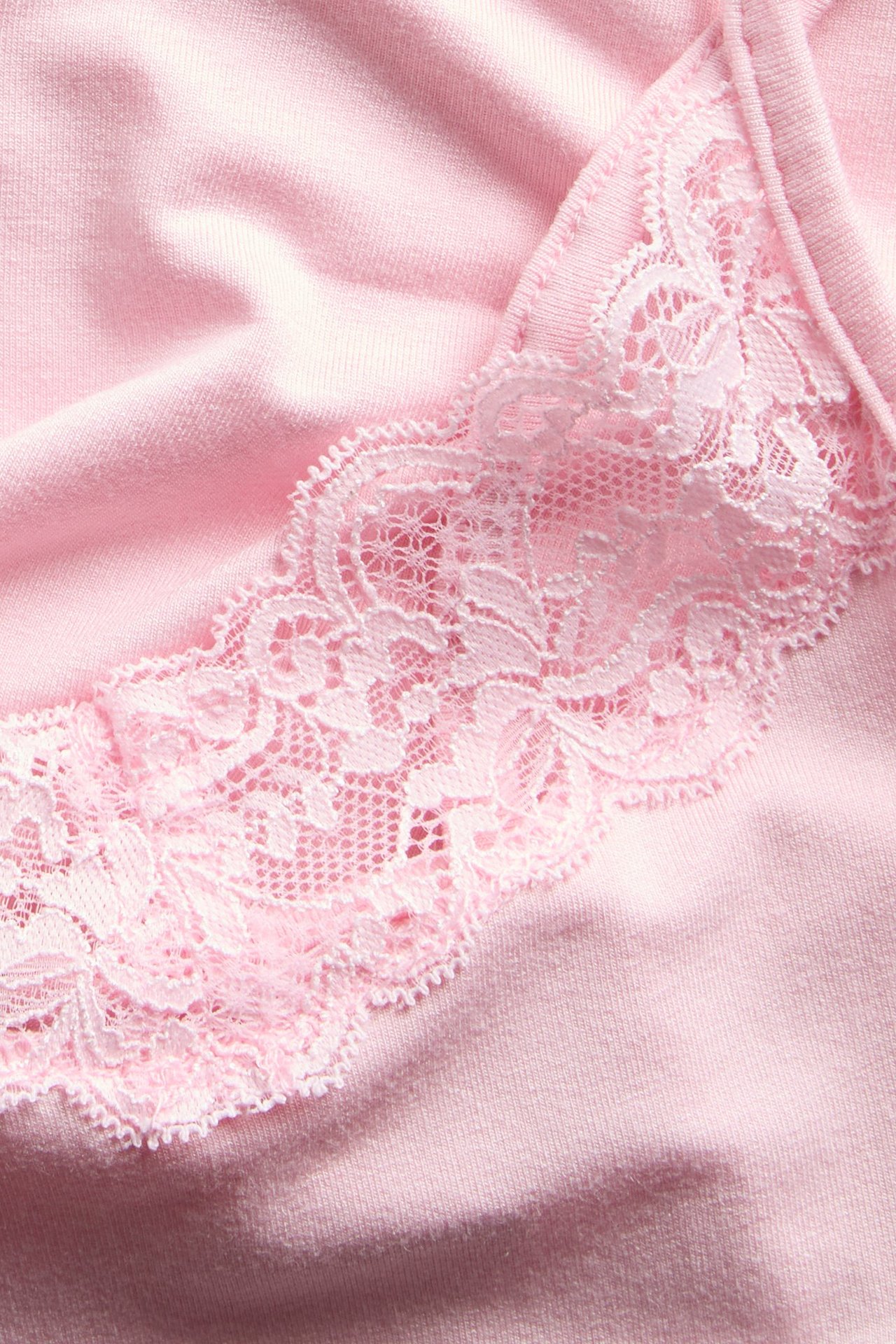 Zbliżenie na różowy top z różową koronkową lamówką przy dekolcie.