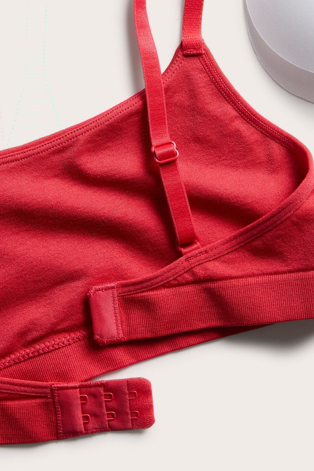 Närbild på en röd sömlös BH med justerbart axelband och hyskknäppning baktill.