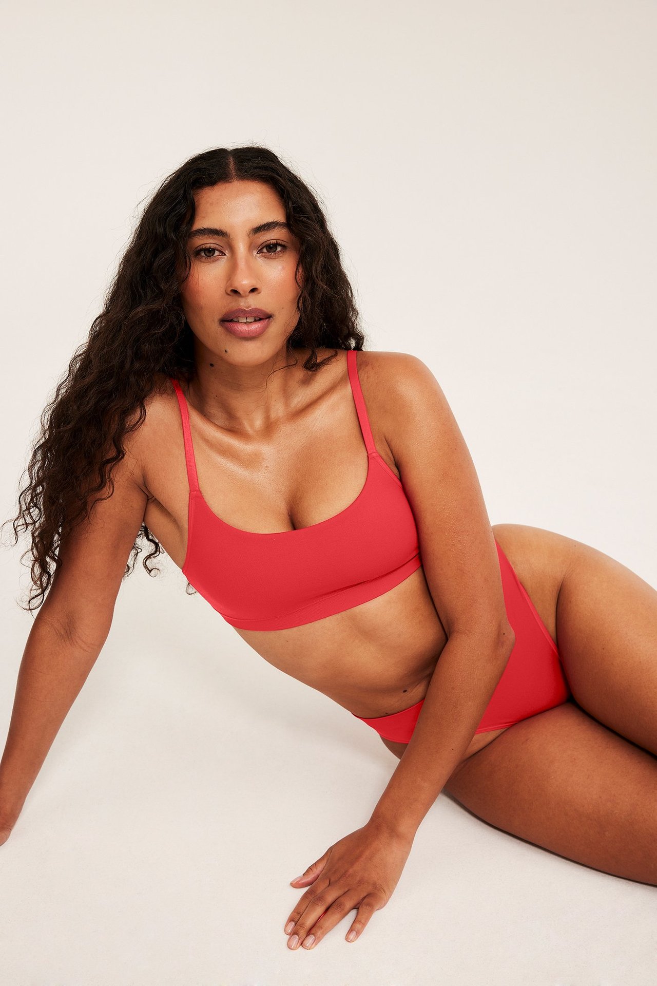 Widok z przodu: kobieta w czerwonym, bezszwowym biustonoszu i pasujących majtkach z wysokim stanem.