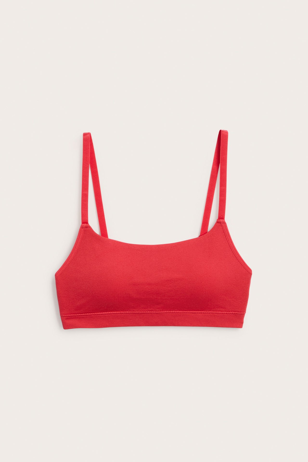 Frontvy av enfärgad röd sömlös BH med tunna, justerbara axelband.
