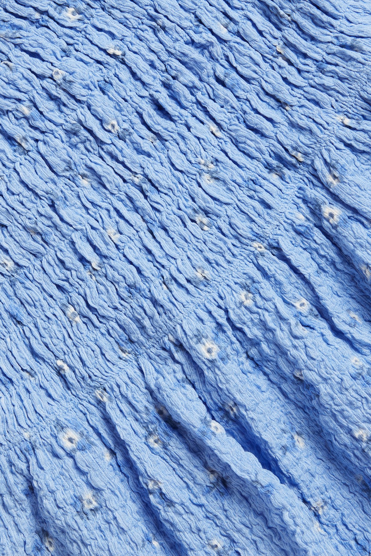 Zbliżenie na jasnoniebieski top w kwiaty z elastycznym marszczeniem, z dżerseju.